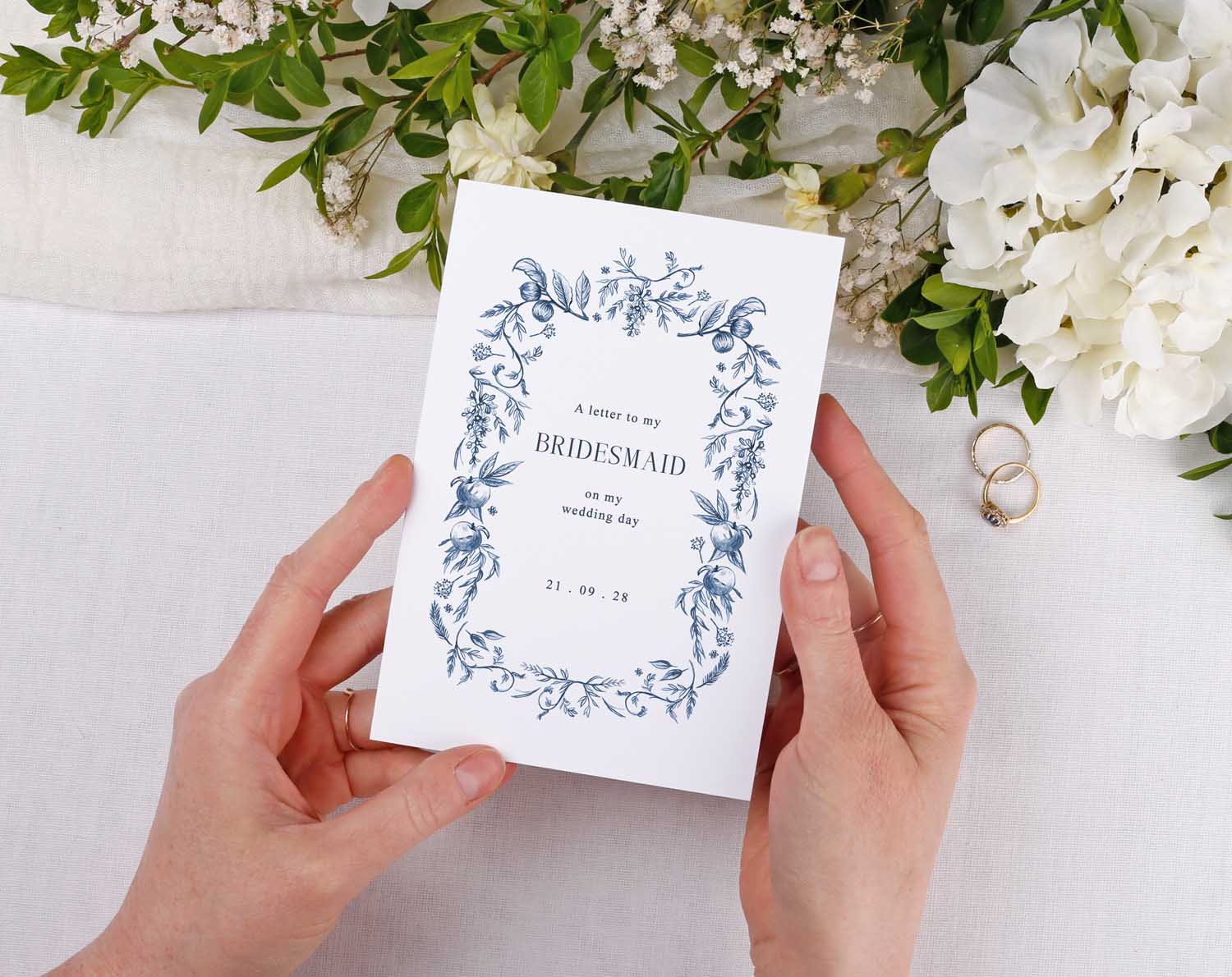 Blue Garden Wedding Thank You Card held by person among flowers and wedding rings.