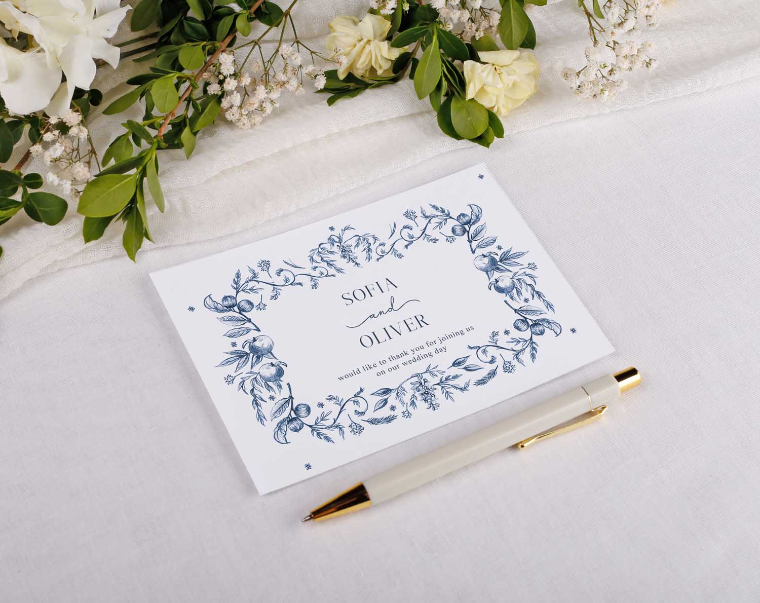 Blue Garden Wedding Thank You Postcards displayed with a pen and floral arrangement on a white fabric background.