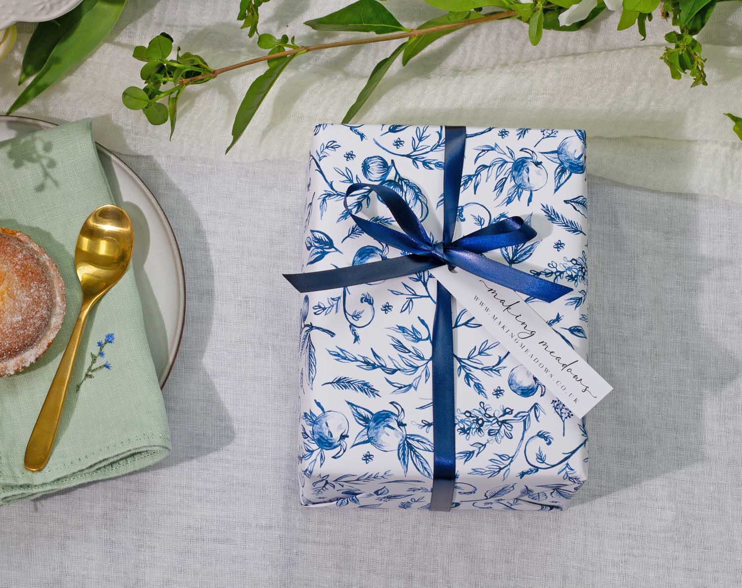 Blue Garden Wedding Wrapping Paper beautifully presented with navy ribbon and tag on a white tablecloth.