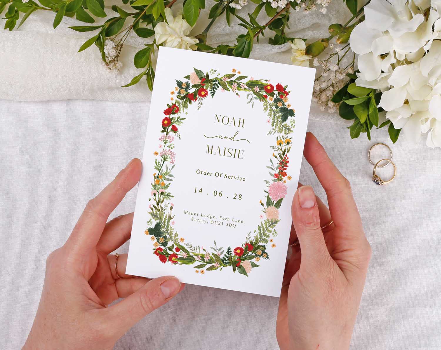 Boho Order Of Service held by hands with floral design for a wedding ceremony.