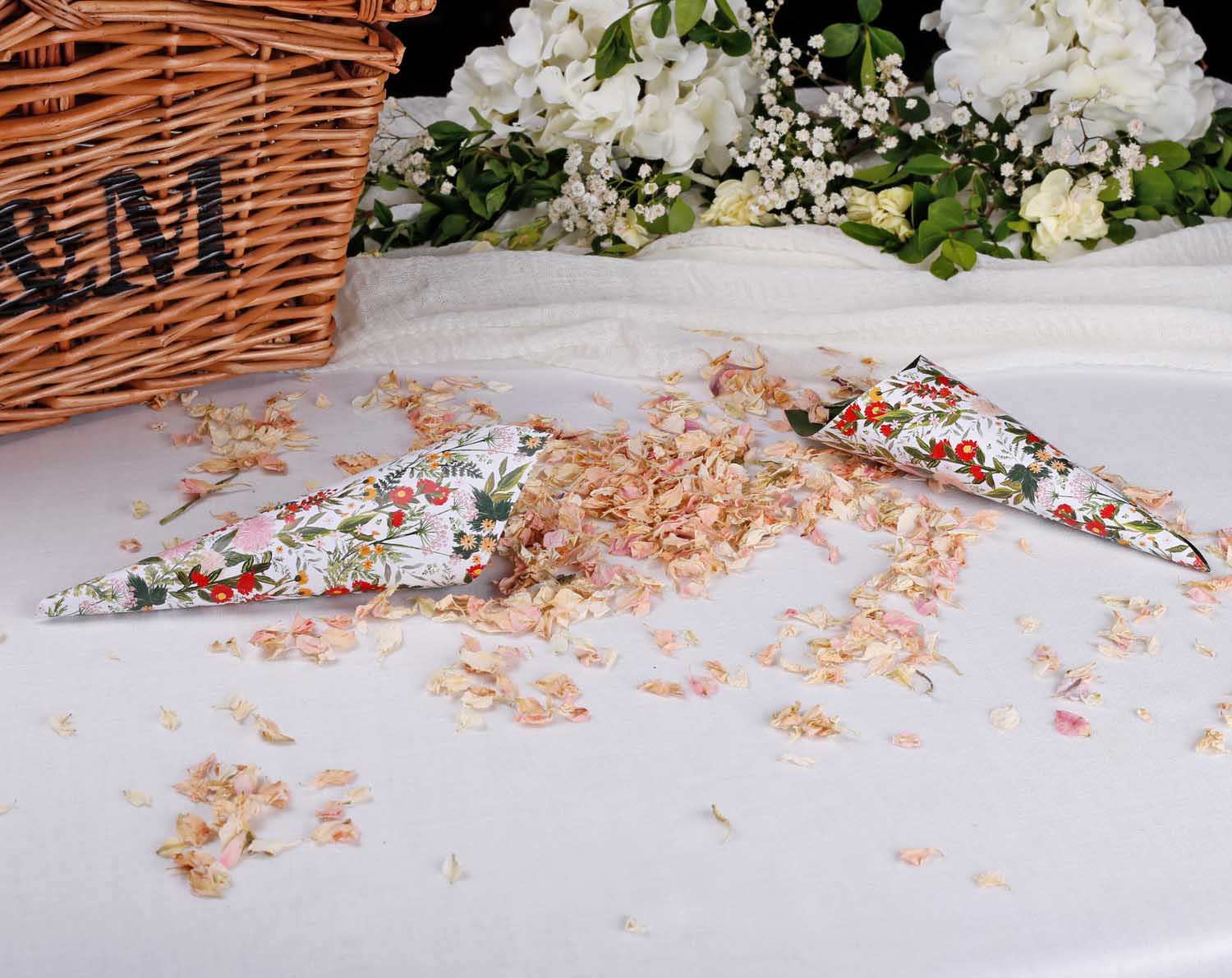 Boho Wedding Confetti Cones scattered with floral confetti on a table beside a woven basket.
