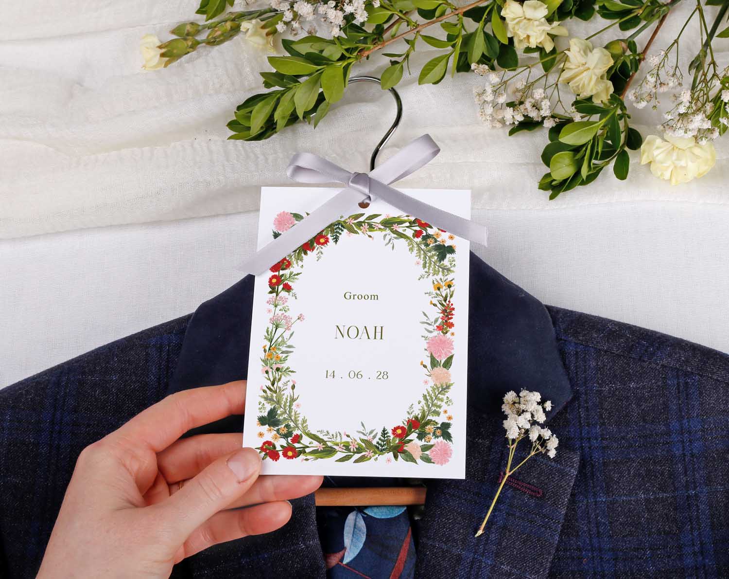 Boho Wedding Hanger Tags for groom Noah featuring floral design and ribbon on a tailored suit.