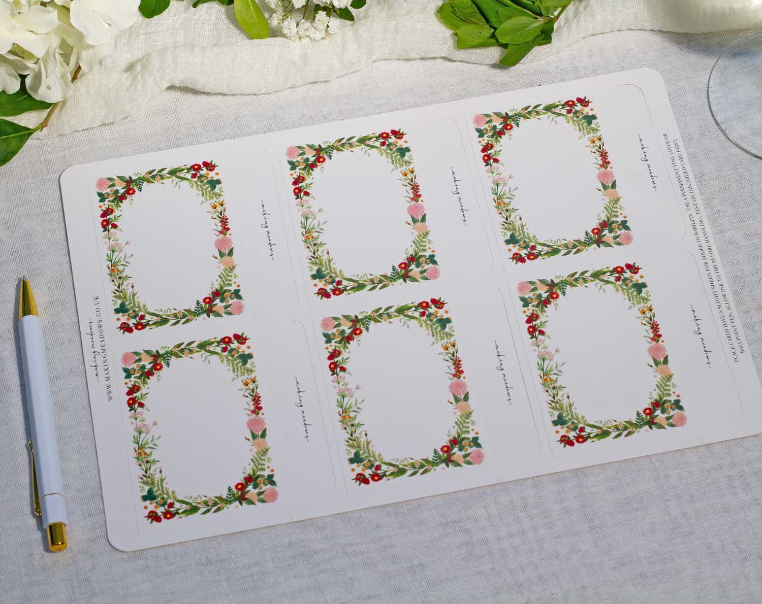 Boho Wedding Place Cards featuring floral designs in pink, red, and green on a table setting.