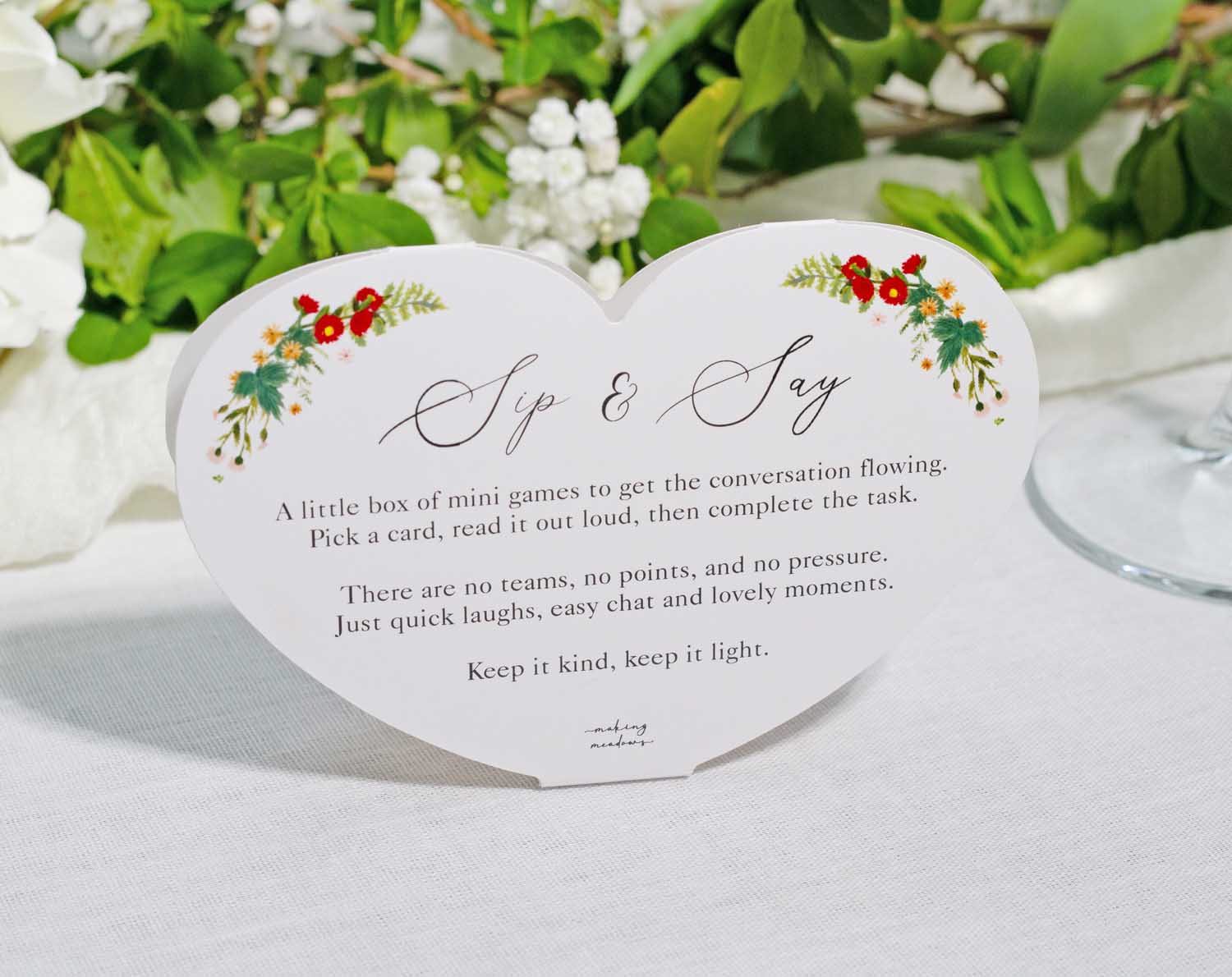 Boho Wedding Table Game Sip and Say mini game card with floral decorations on a table.