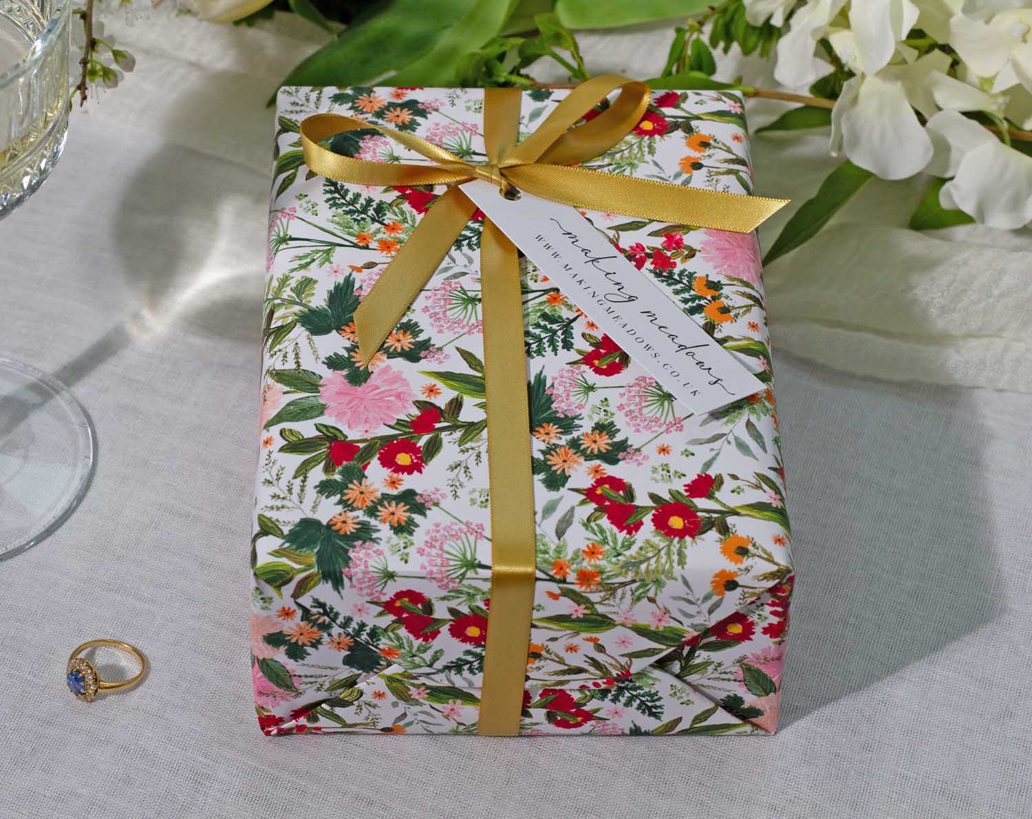 Boho Wedding Wrapping Paper beautifully wraps a gift with floral design and golden ribbon, perfect for celebrations.