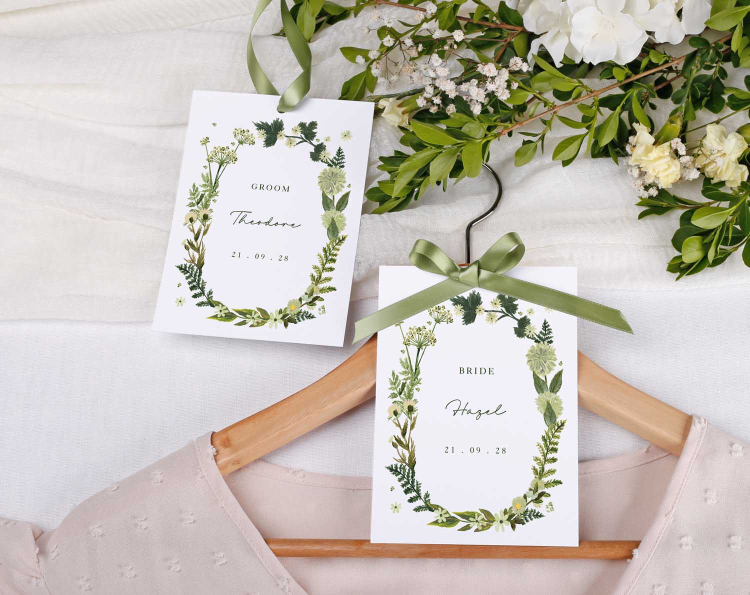 Botanical Wedding Hanger Tags with ribbon featuring bride and groom names surrounded by greenery.