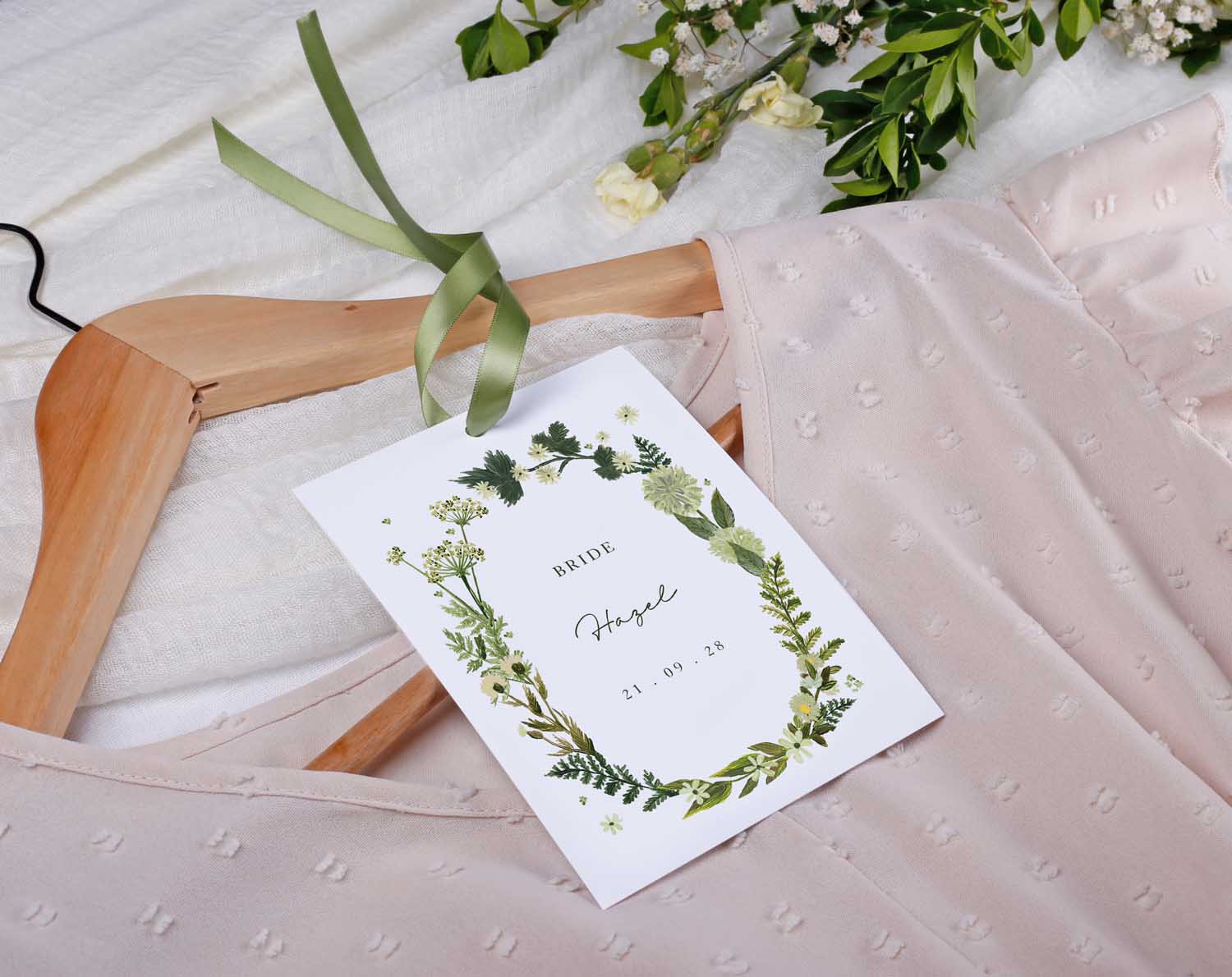 Botanical Wedding Hanger Tags with ribbon displayed on a dress hanger, featuring greenery and personalized details.