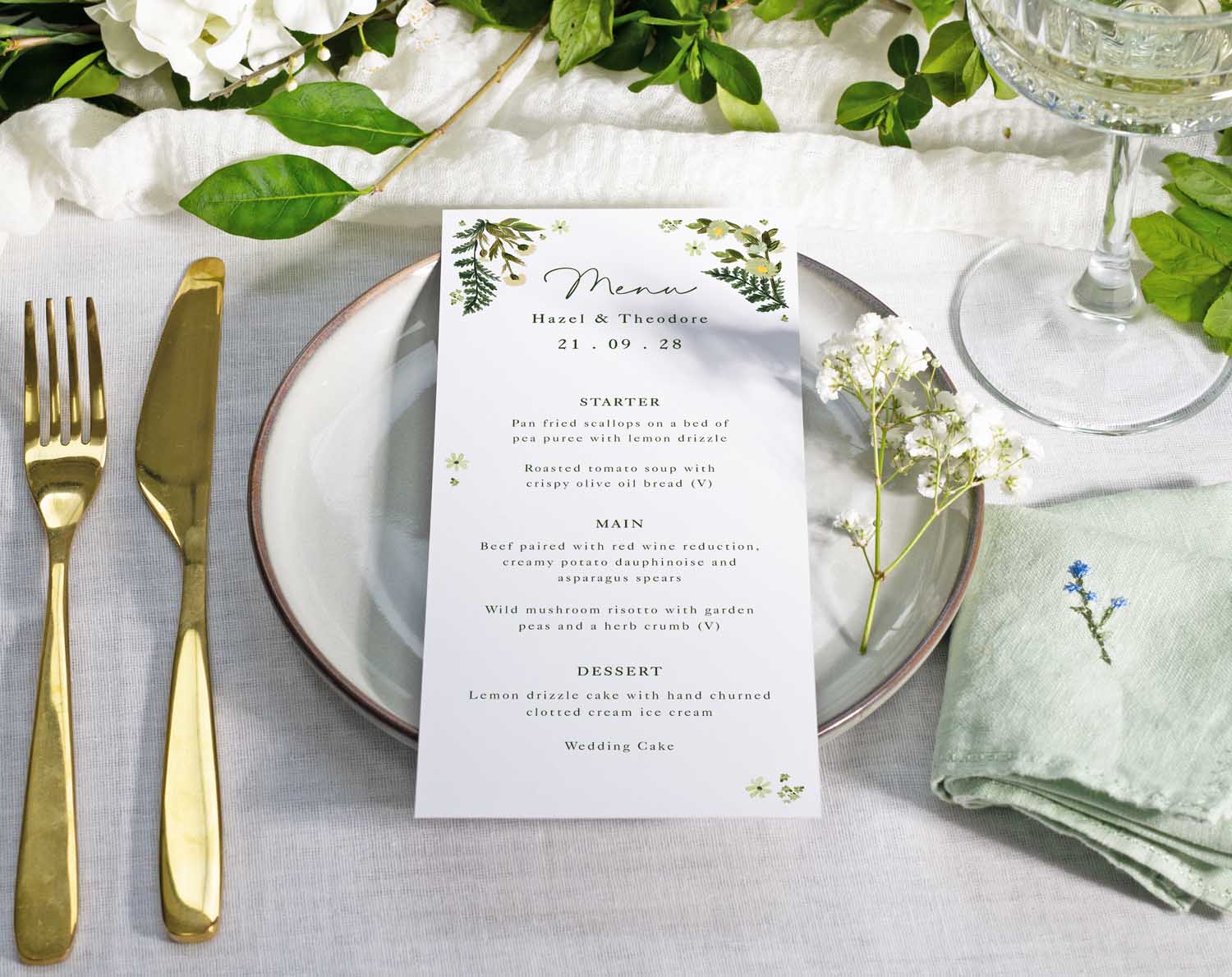 Botanical Wedding Menus displayed elegantly on a table setting with a plate, cutlery, and floral decor.