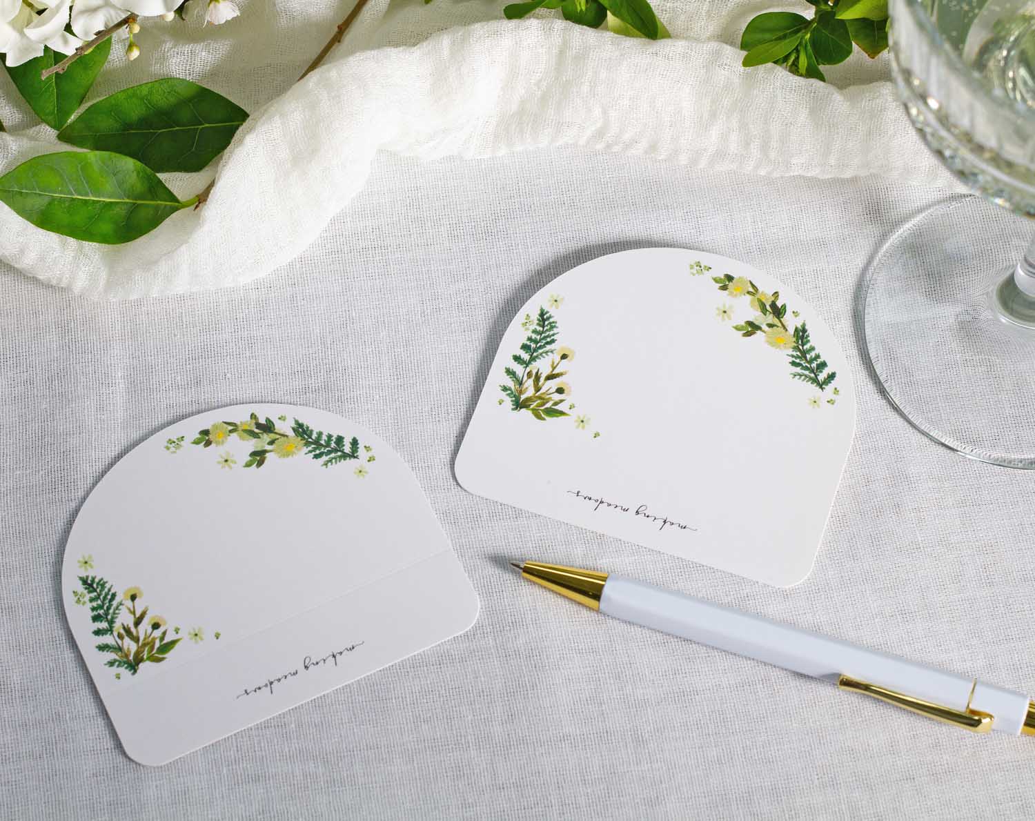 Botanical Wedding Place Cards featuring lush greenery and fern designs on a table setting.