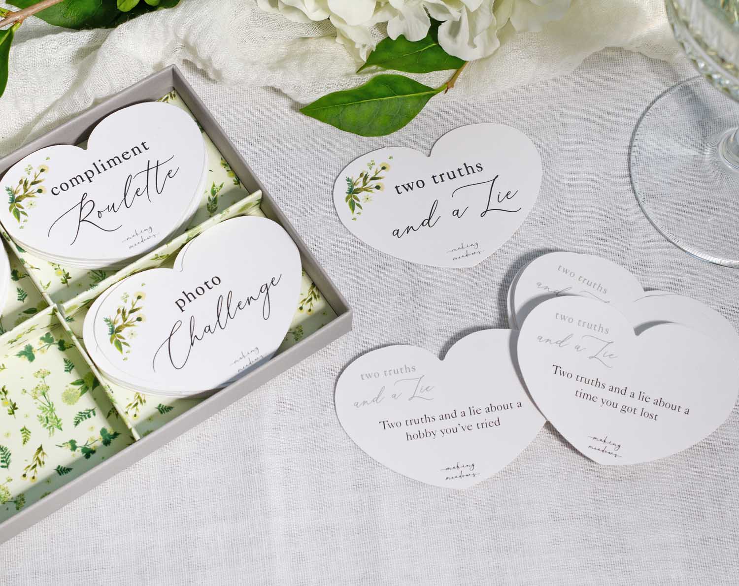 Botanical Wedding Table Game featuring heart-shaped cards for Compliment Roulette and Two Truths and a Lie.