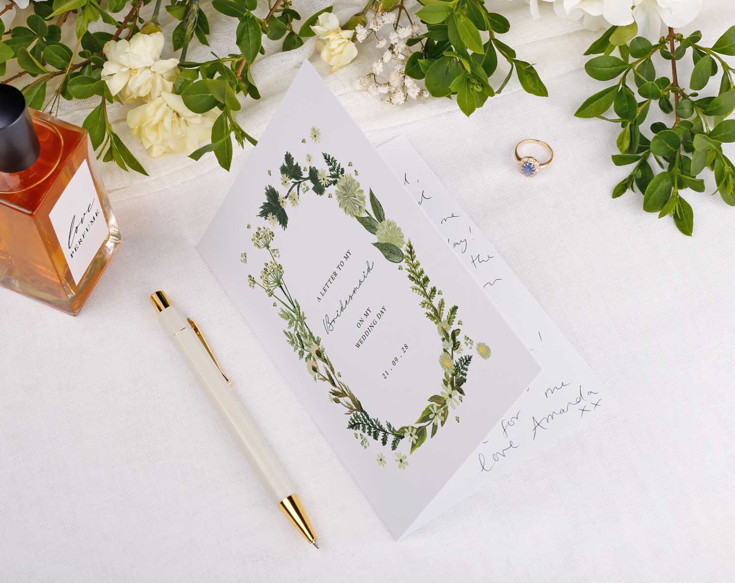 Botanical Wedding Thank You Card featuring floral designs, a pen, and a perfume bottle on a soft cloth background.