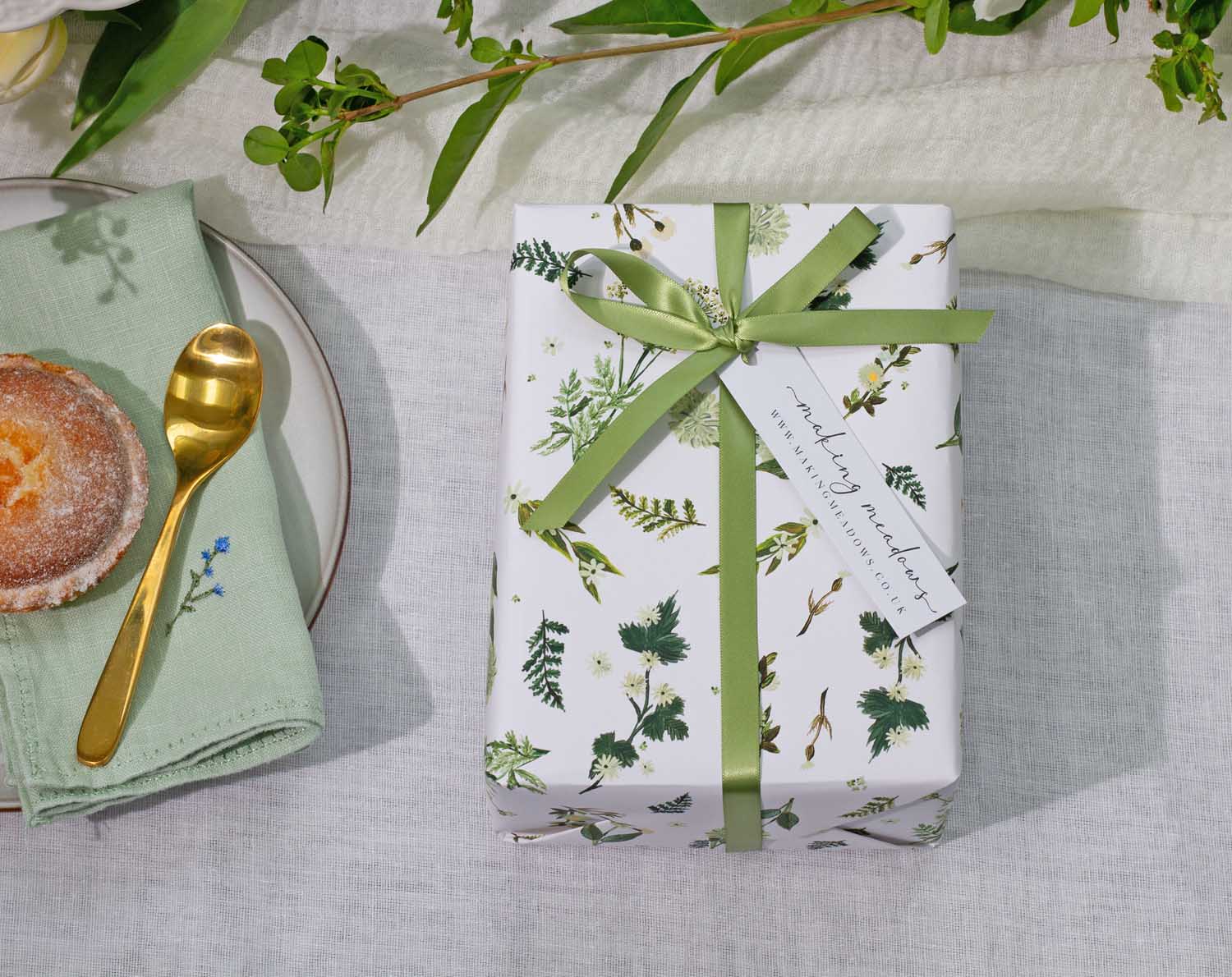 Botanical Wedding Wrapping Paper featuring hand-drawn botanical designs and a green ribbon on a table setting.