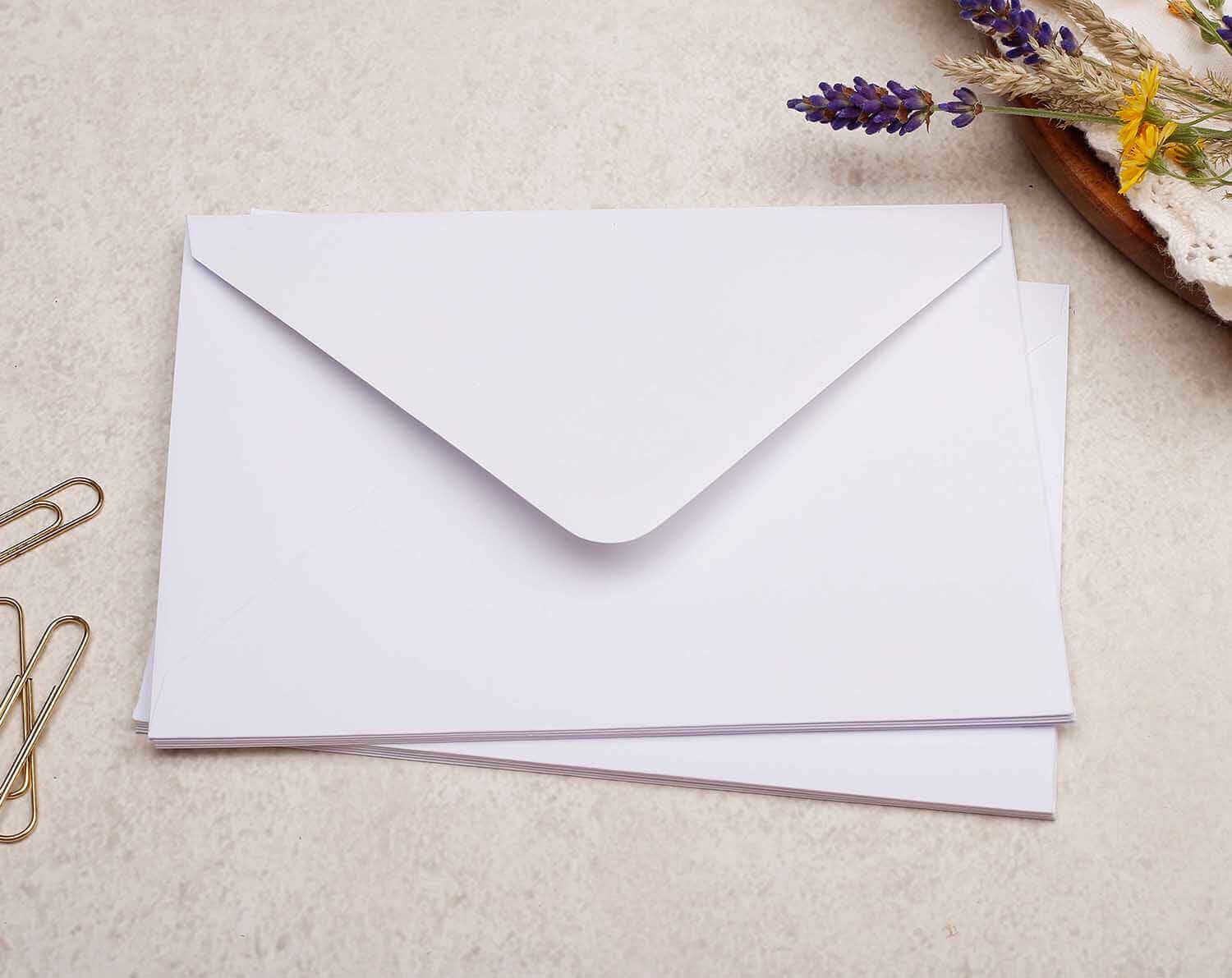 C6 Unicorn Decorated Envelopes displayed on a surface surrounded by paperclips and flowers.