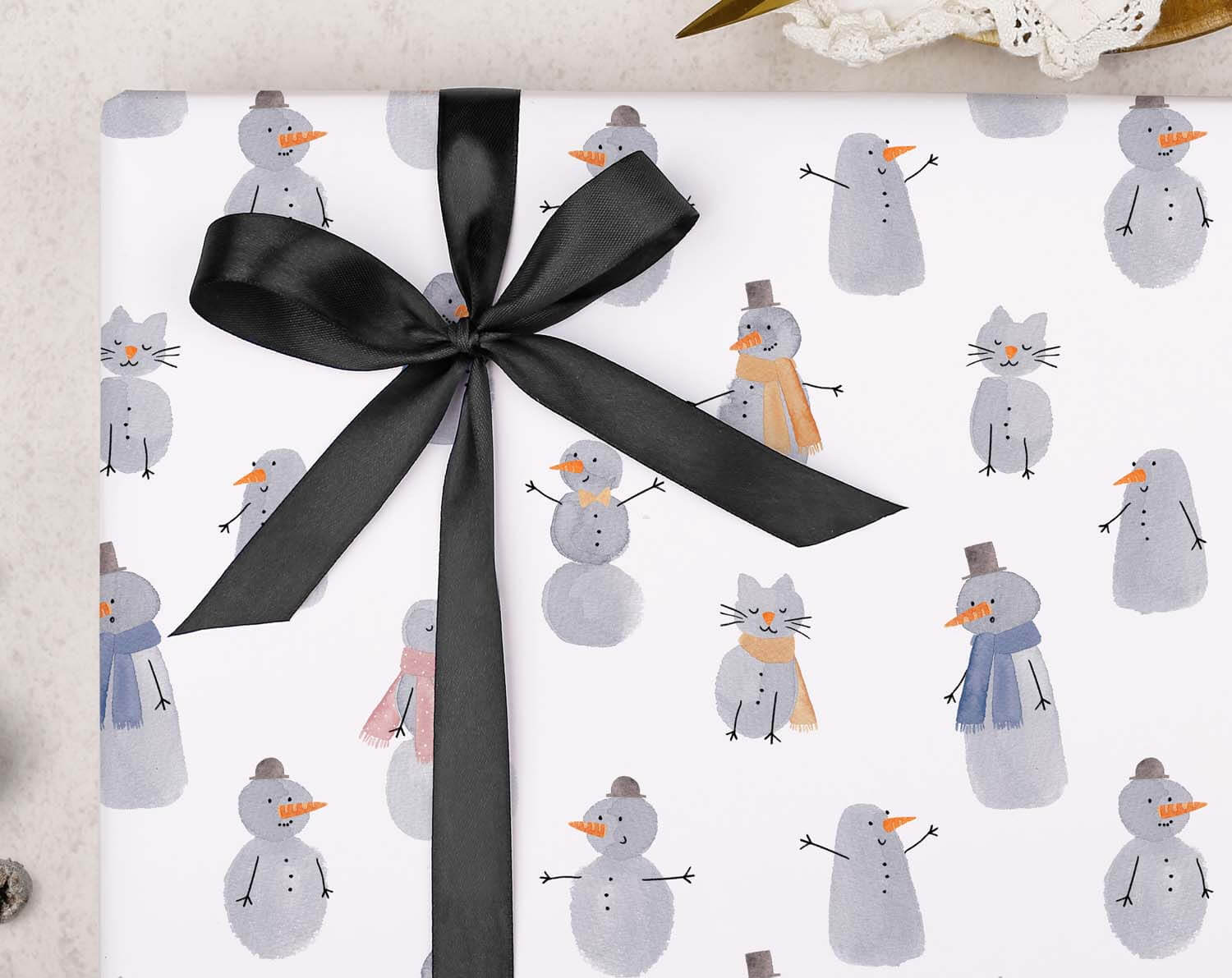 Children's Snowmen Christmas Wrapping Paper featuring adorable snowmen illustrations and a black ribbon.