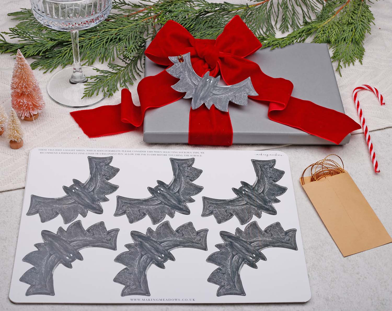 Bat Christmas Gift Tags - 12 Pack displayed with gift, red ribbon, and holiday decorations.