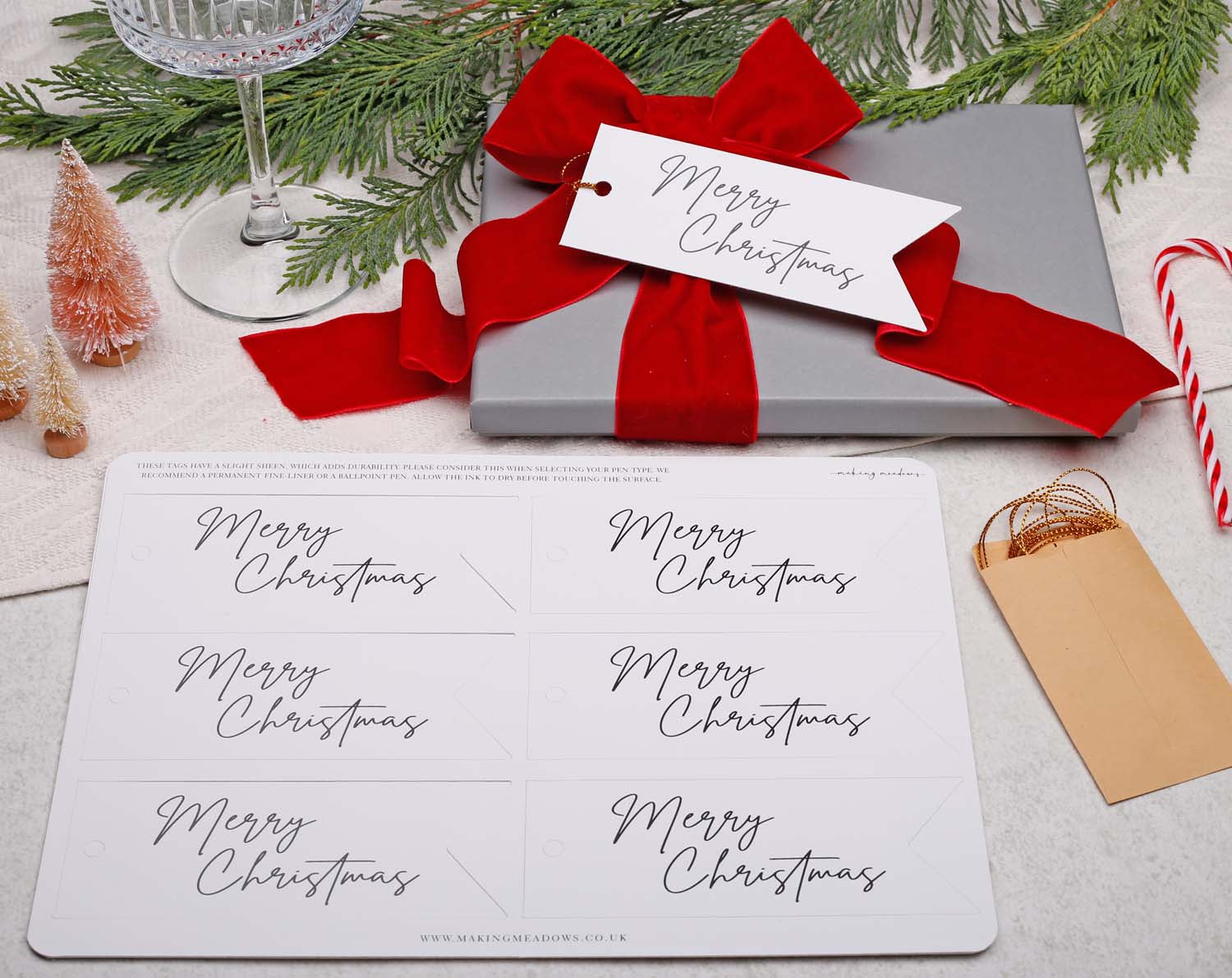 Merry Christmas Gift Tags displayed on a gift box with red ribbon alongside a festive background.