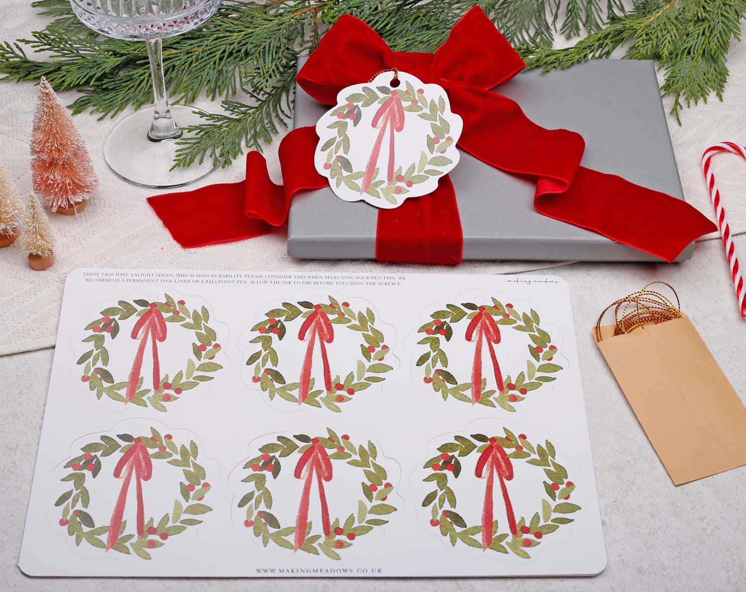 Wreath Christmas Gift Tags displayed on a wrapped gift box with a red ribbon and festive decorations.
