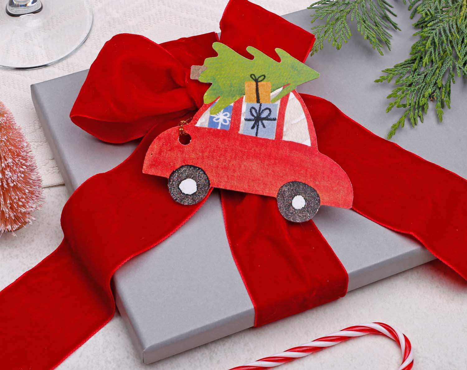 Car Christmas Gift Tags on a Christmas gift wrapped in red ribbon with a festive decoration.