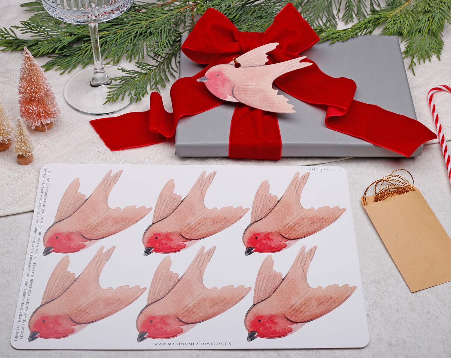 Robin Christmas Gift Tags - 12 Pack displayed on a gift with a red bow and Christmas decorations.