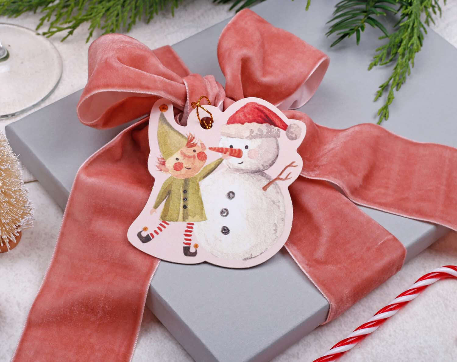 Elf Christmas Gift Tags featuring an elf and snowman illustration on a gift box with a pink ribbon.
