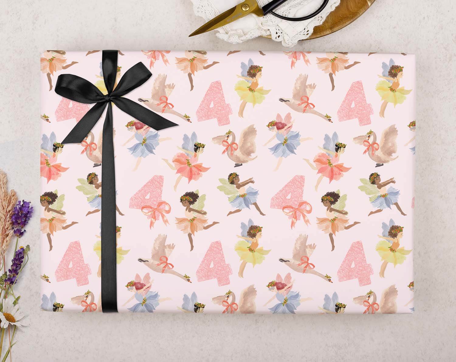 Fairy 4th Birthday Wrapping Paper featuring pink fairy design and number 4, tied with a black ribbon.