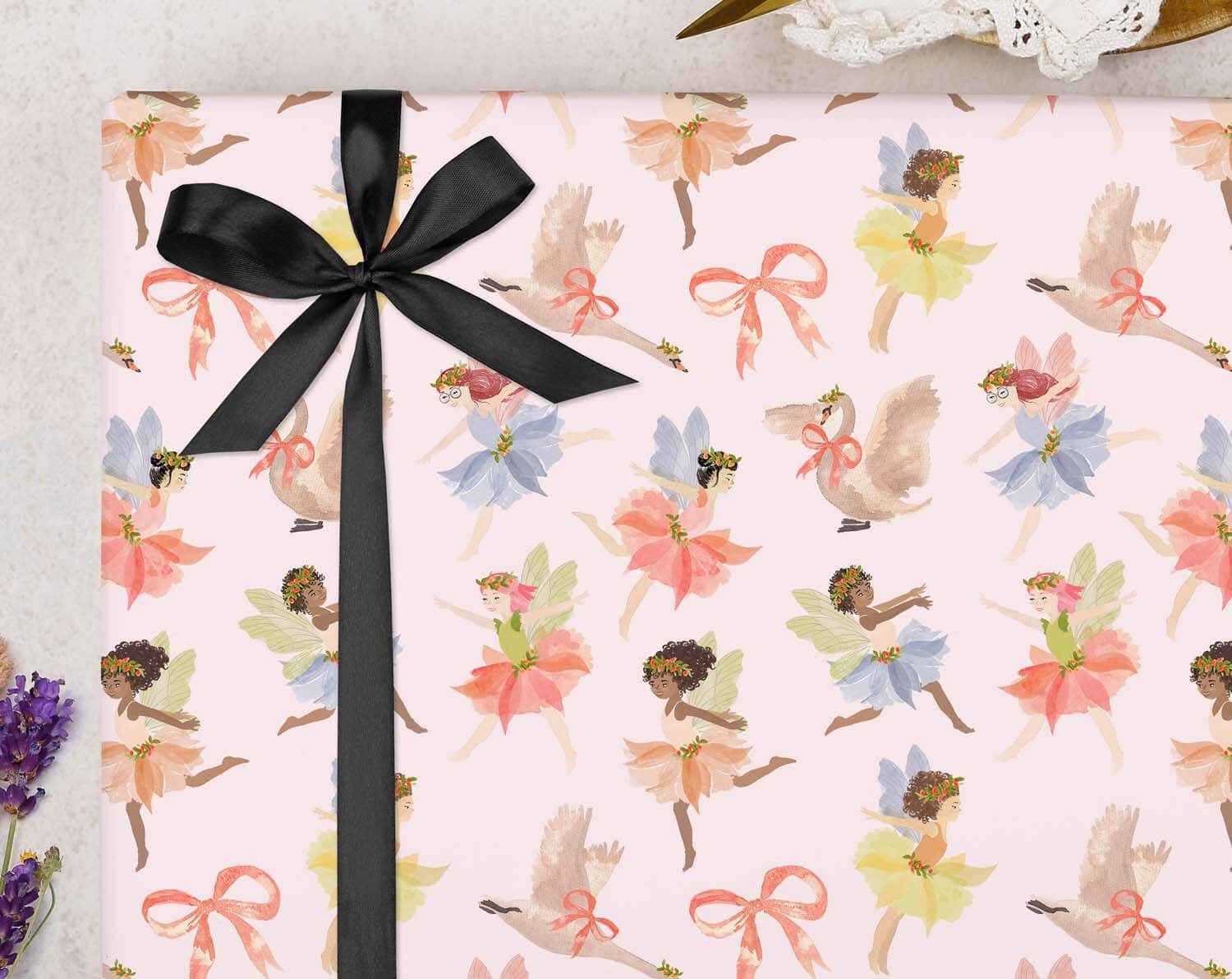 Fairy Wrapping Paper featuring colorful fairies and bows on a pink background, tied with a black ribbon.