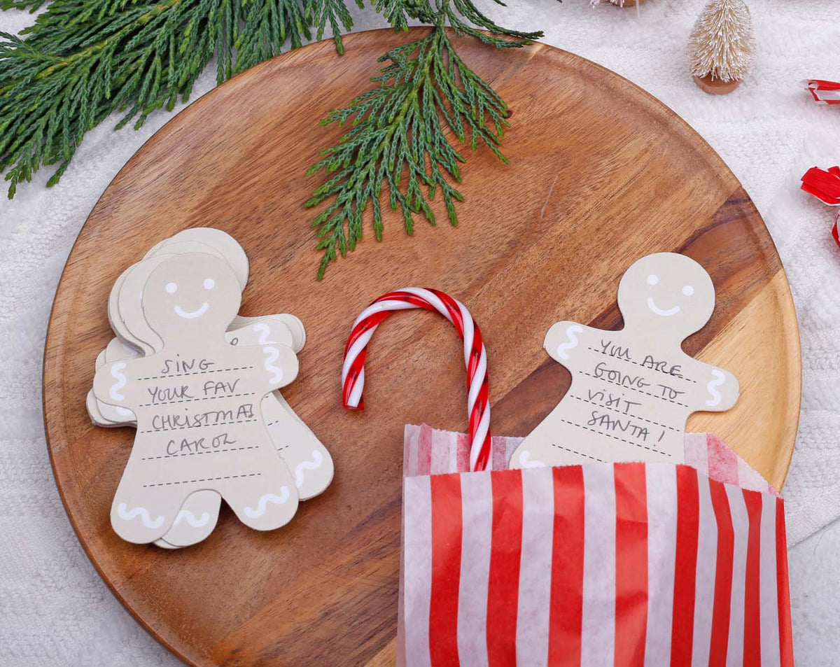 Gingerbread Fill Your Own Activity Cards displayed on a wooden platter with festive decorations and candy cane.