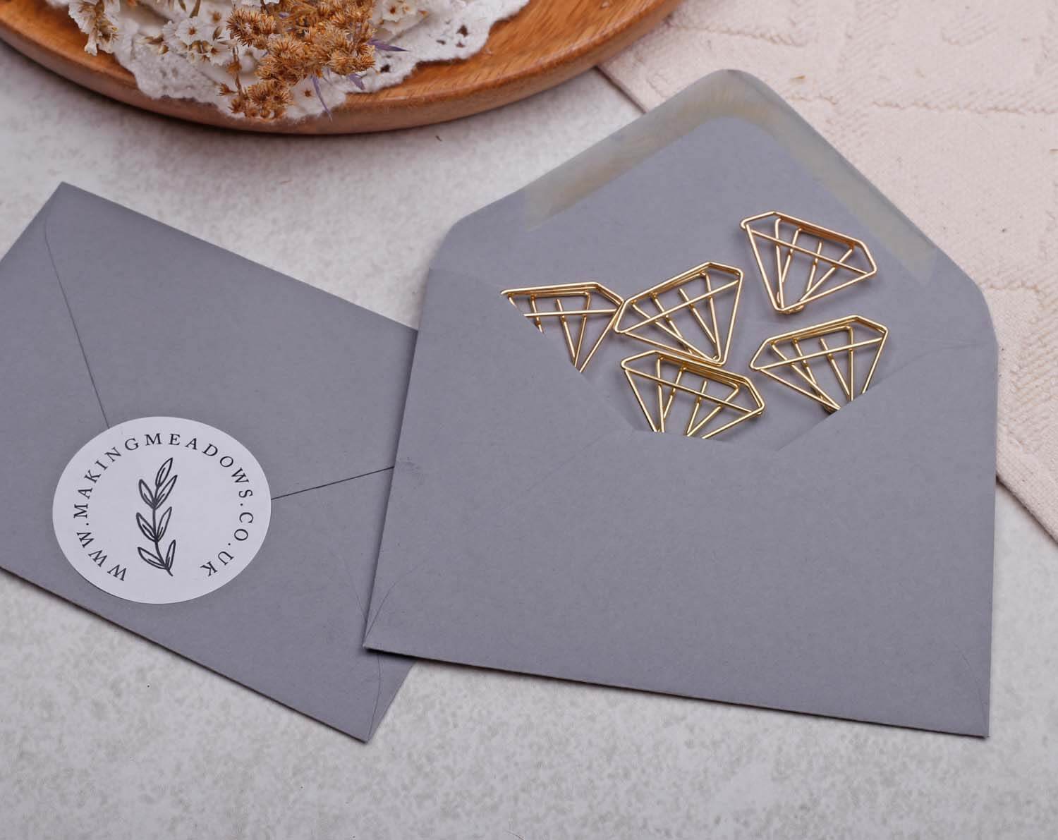 Gold Diamond Paper Clips shaped and packaged inside a gray envelope.