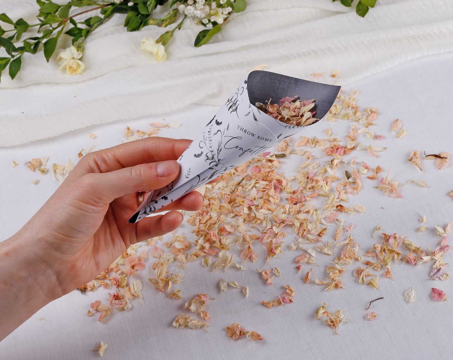 Gothic Wedding Confetti Cones held with flower petals scattered around for wedding ceremony decor.