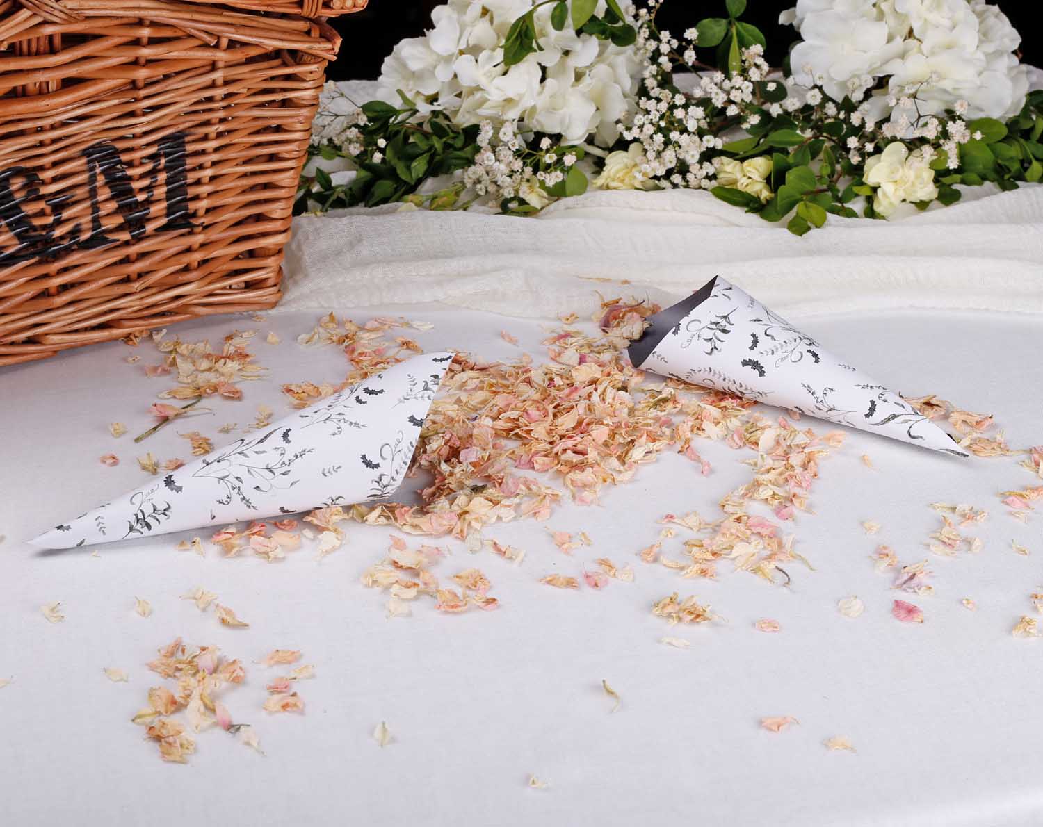 Gothic Wedding Confetti Cones scattered with dried flower petals beside a wicker basket.