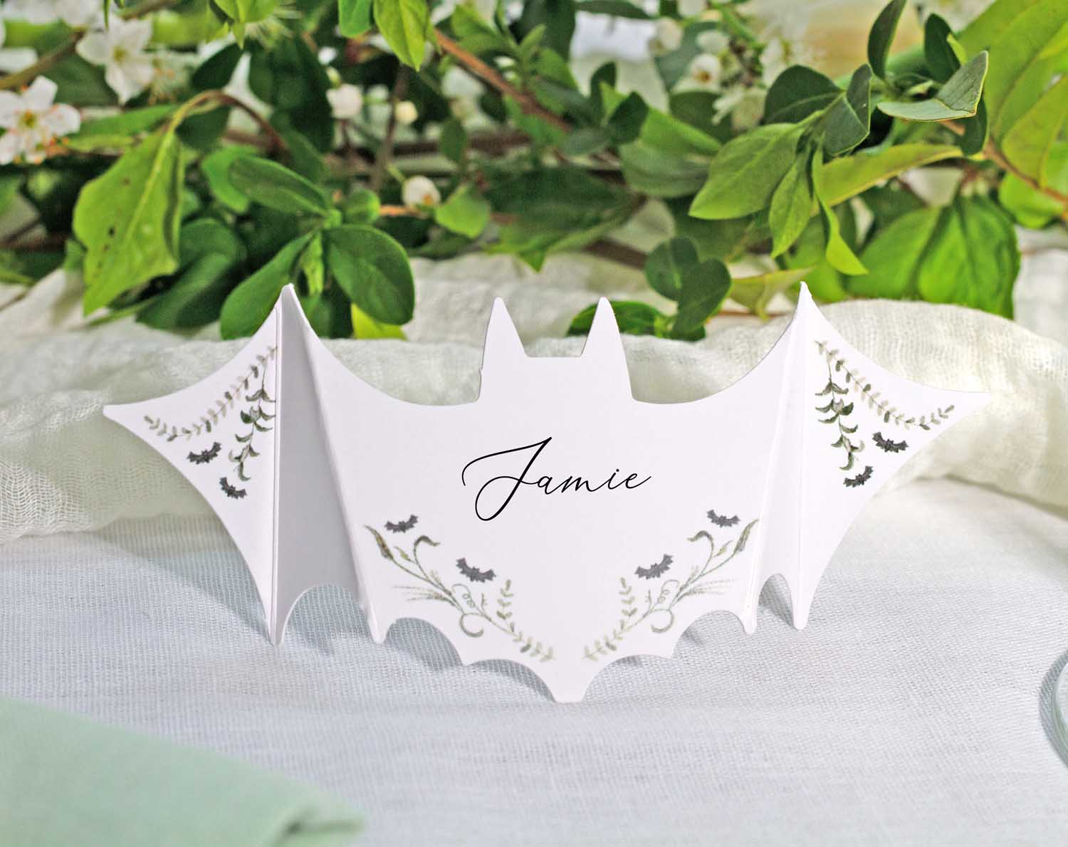 Gothic Wedding Place Cards featuring a bat shape personalized with the name Jamie, set on a beautiful table setting.