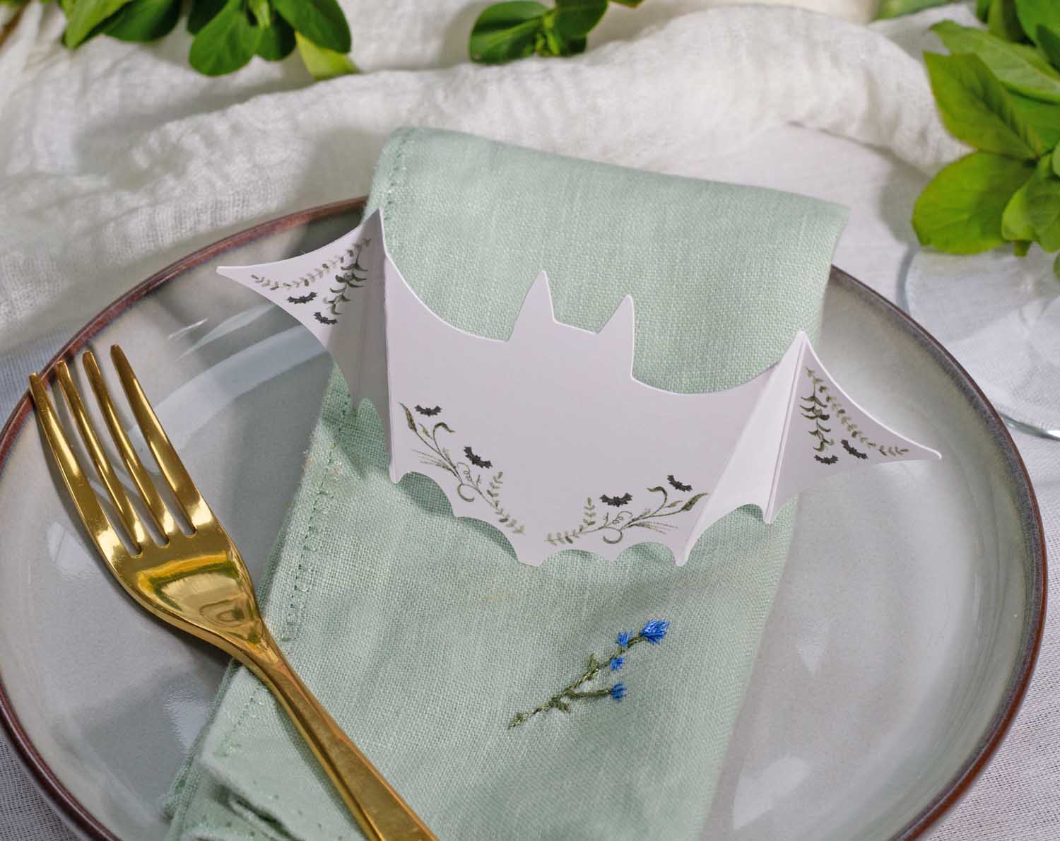 Gothic Wedding Place Cards featuring a bat design on a table setting with a green napkin and gold fork.
