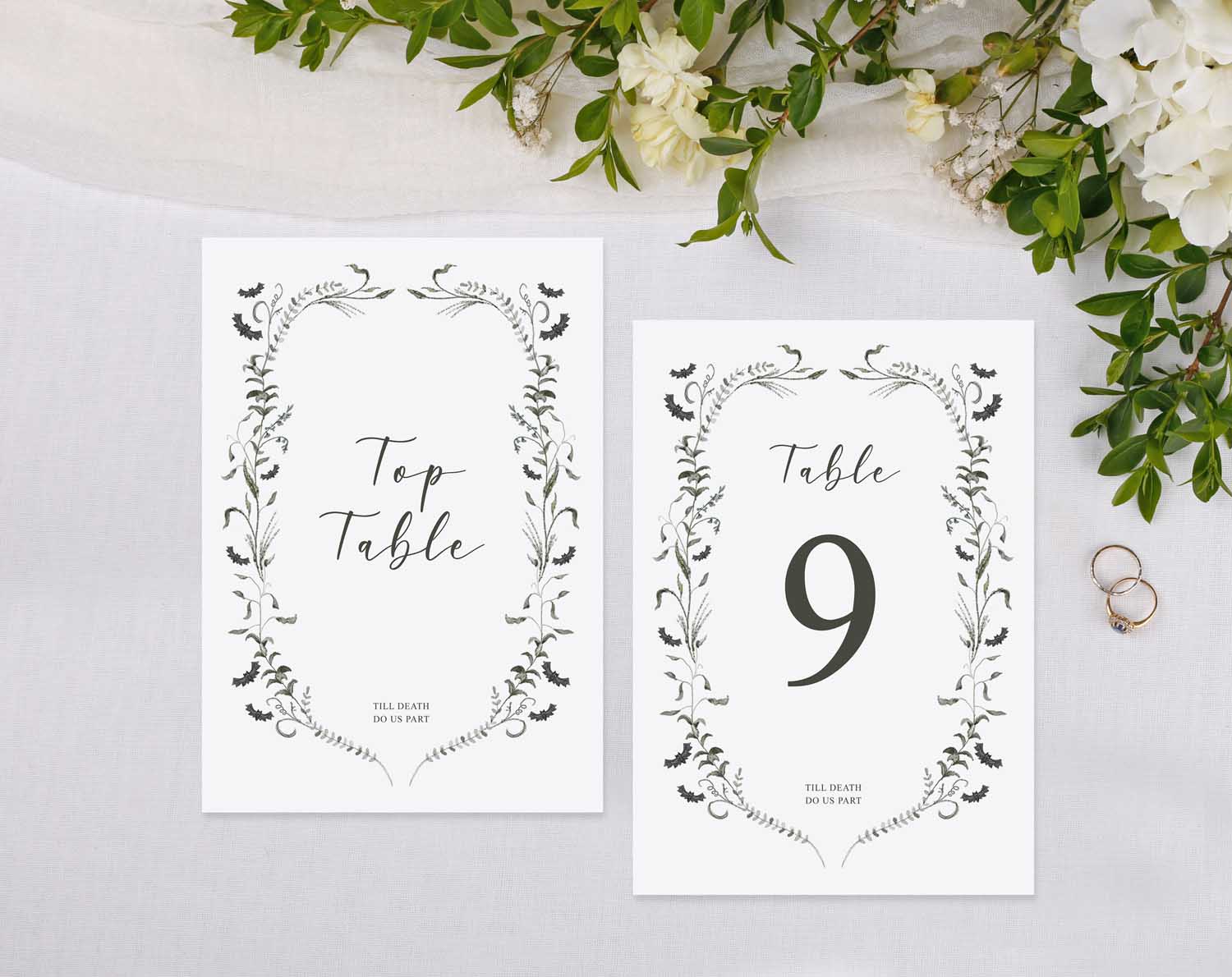 Gothic Wedding Table Numbers displayed on a table with floral arrangement and wedding rings.