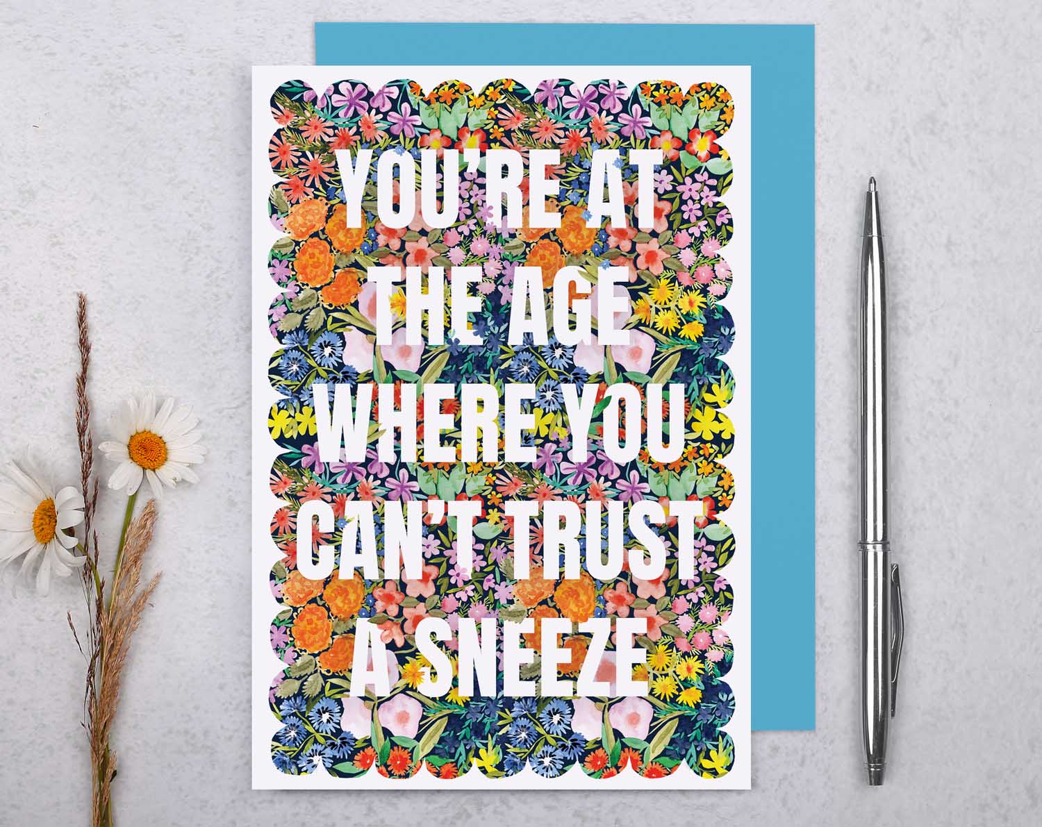 Joke Birthday Card featuring colorful floral design with the text 'You’re at the age where you can’t trust a sneeze'.
