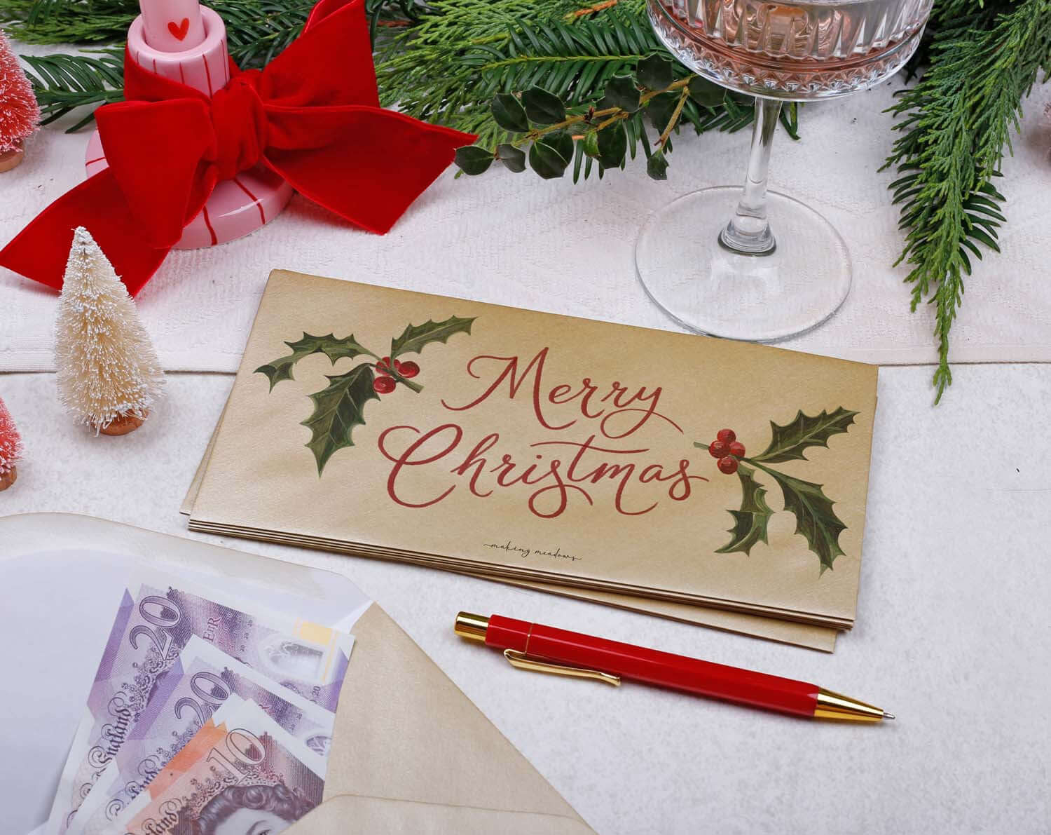 Holly Christmas Money Envelopes - Gold Pack featuring holly illustrations and Merry Christmas text on a festive table setting.