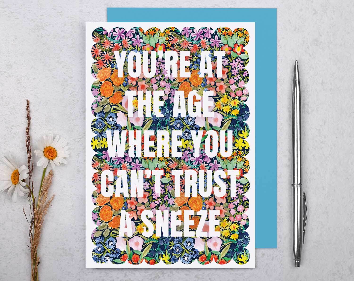 Joke Birthday Card featuring colorful floral design with the text 'You’re at the age where you can’t trust a sneeze'.