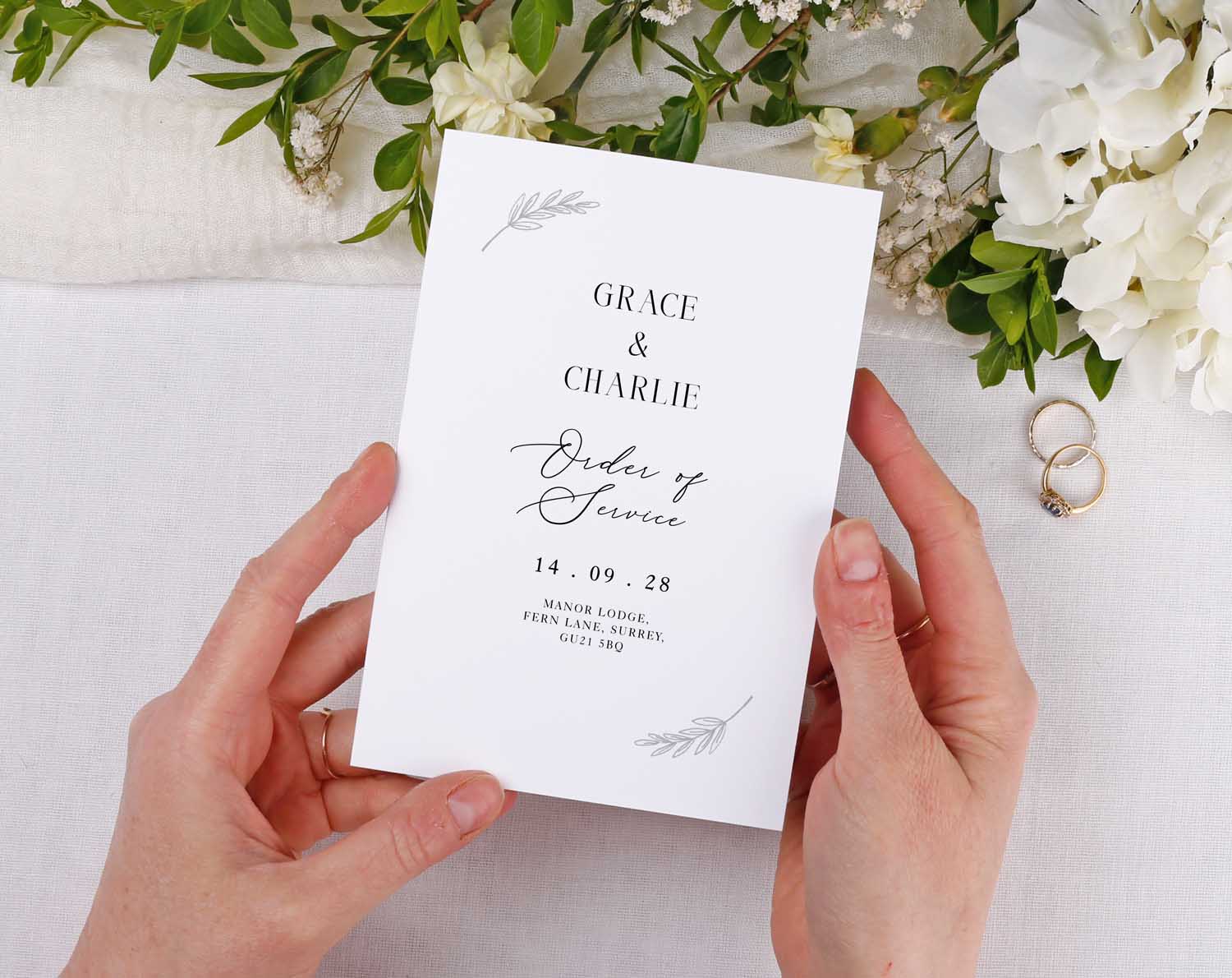 Minimalist Order Of Service booklet held in hands, featuring elegant typography and floral details.
