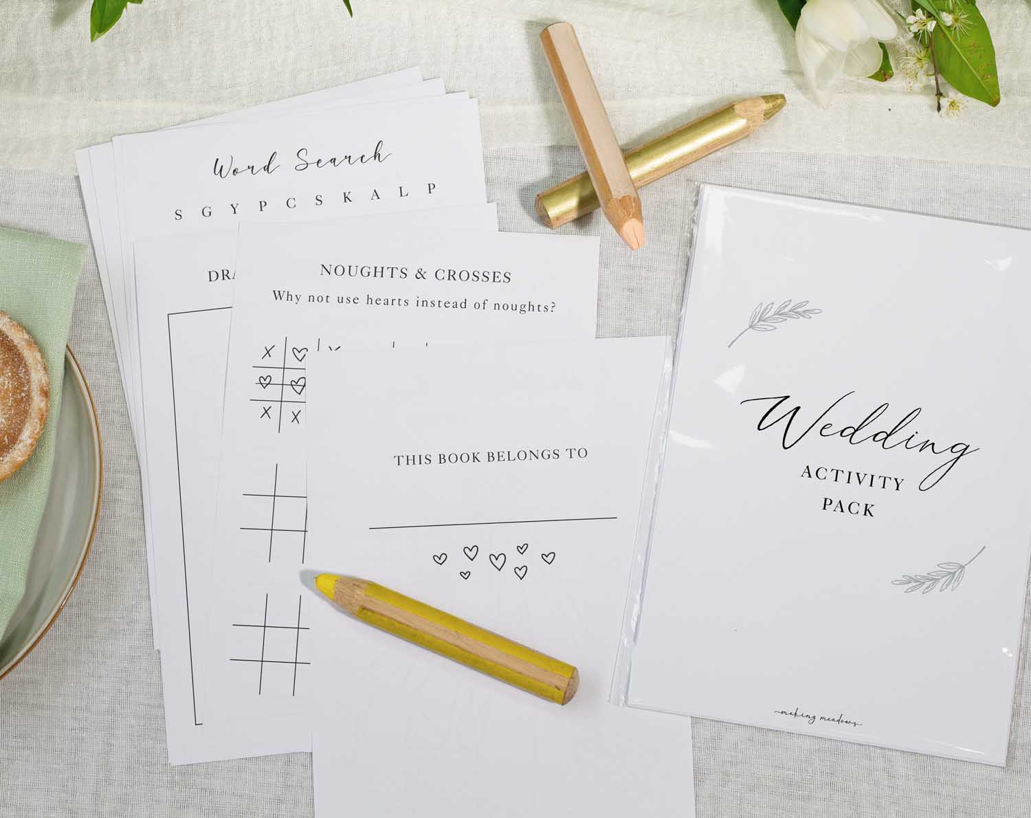 Minimalist Wedding Kids Activity Pack featuring activity sheets and crayons on a wedding table.