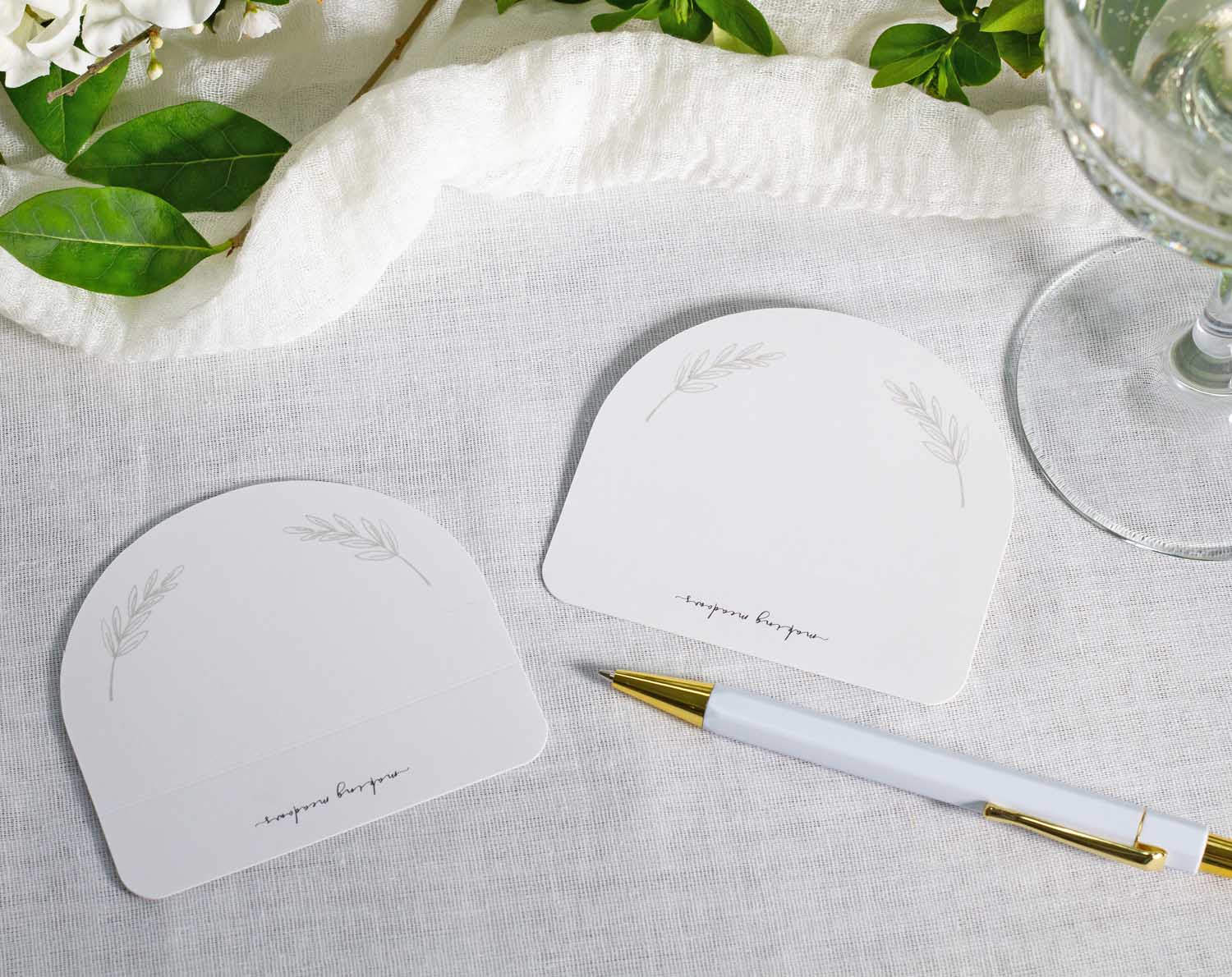 Minimalist Wedding Place Cards displayed on a table setting with greenery and a pen for elegant wedding decor.