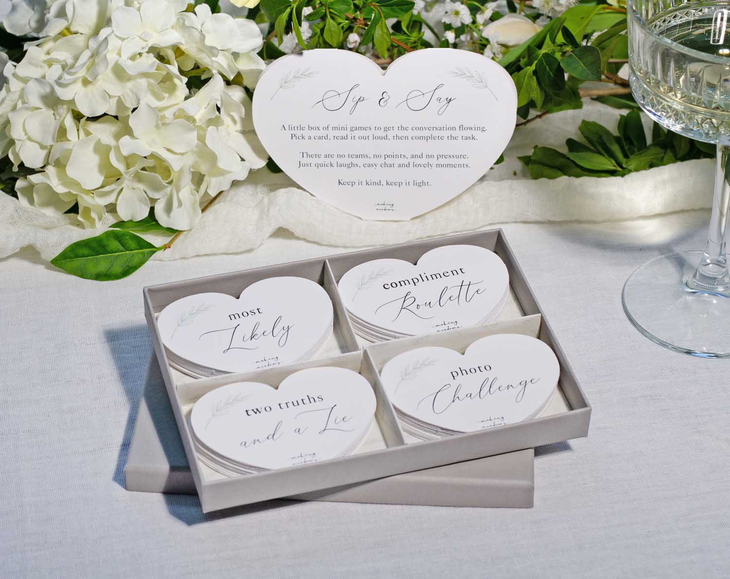 Minimalist Wedding Table Game with Sip & Say cards and floral background for interactive wedding fun.