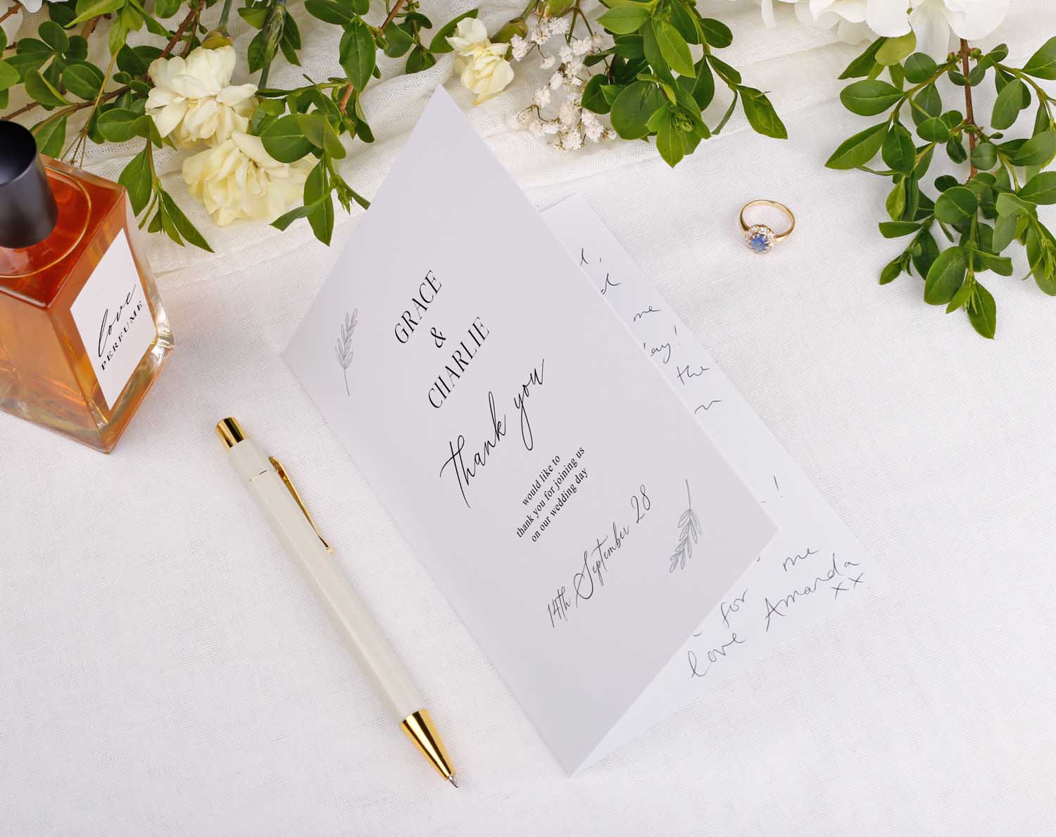 Minimalist Wedding Thank You Cards displayed on a table with flowers, a pen, and a ring.
