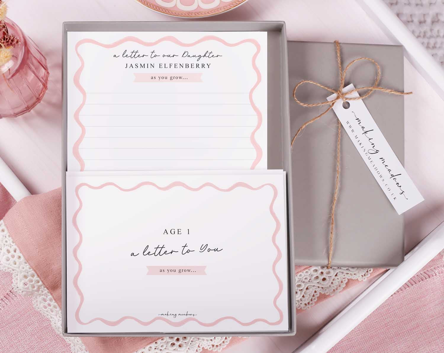 Personalised Pink Wavy Letter To Our Daughter set displayed in a gift box with pink scalloped edges.