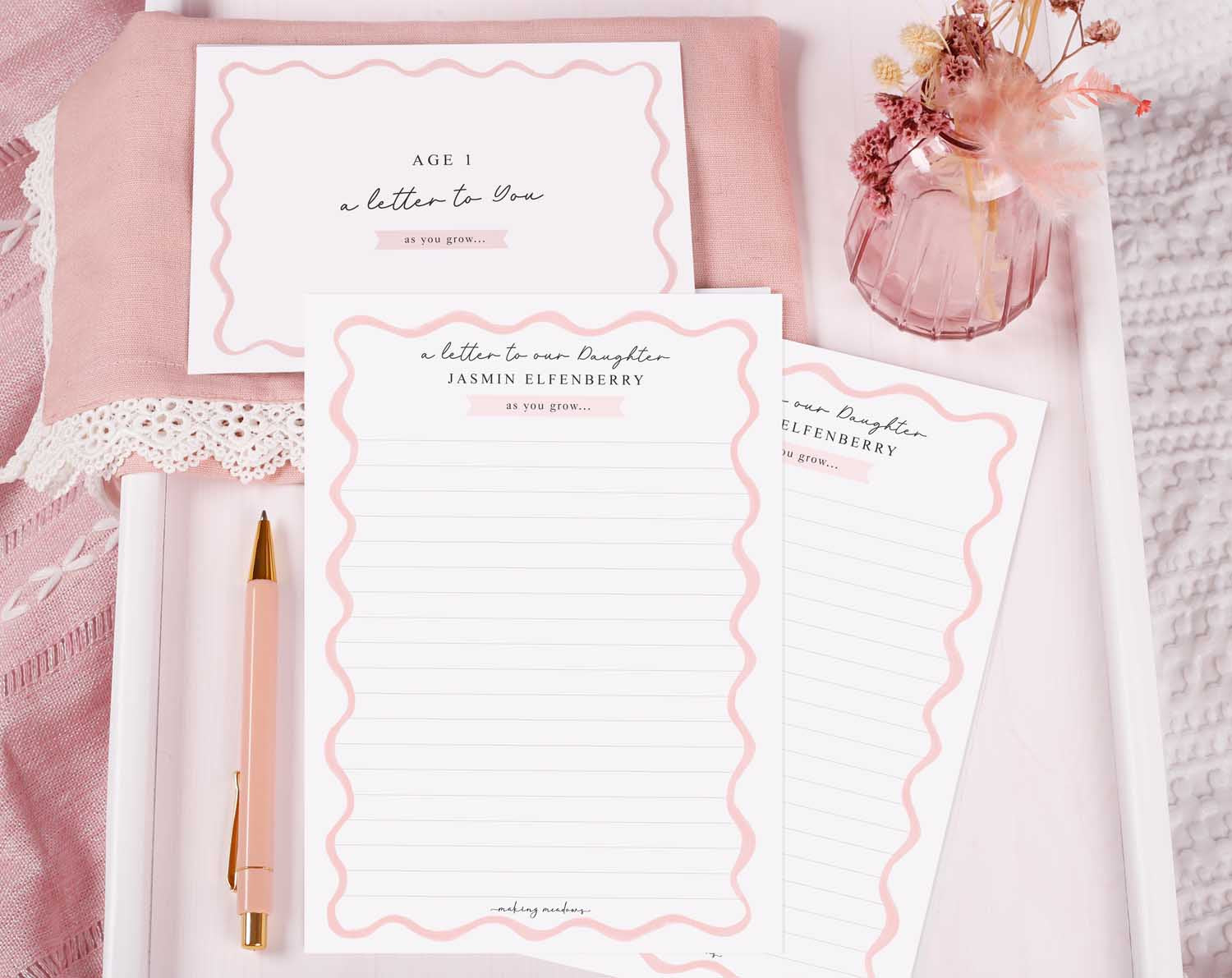 Personalised Pink Wavy Letter To Our Daughter set displayed on a soft pink background with stationery and a pen.