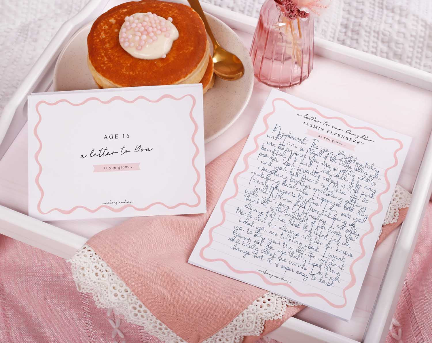 Personalised Pink Wavy Letter To Our Daughter set on a tray with pancakes and a flower vase, perfect gift for lasting memories.