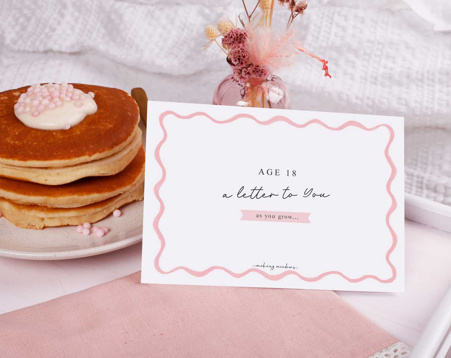 Personalised Pink Wavy Letter To Our Daughter displayed alongside pancakes and floral decor.