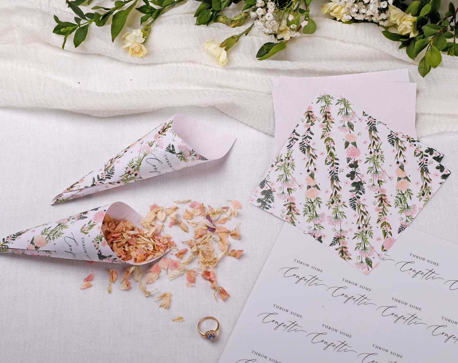 Pink Floral Wedding Confetti Cones filled with dried petals, surrounded by floral decorations and wedding stationery.