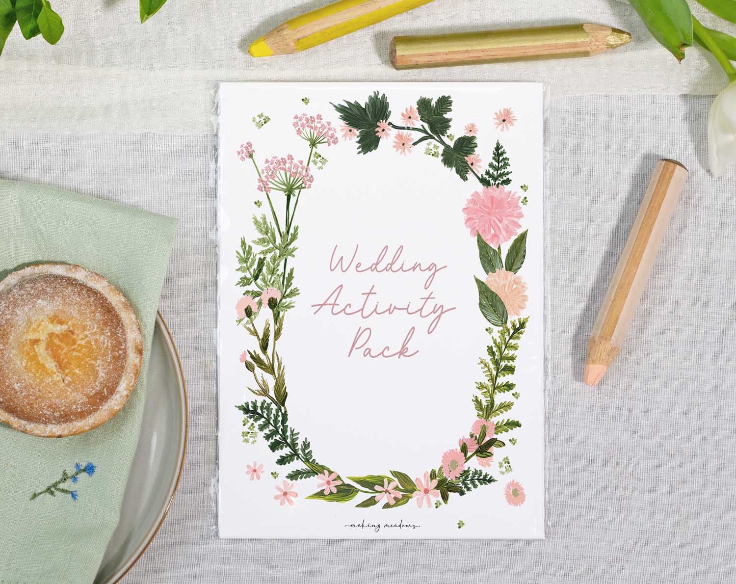 Pink Floral Wedding Kids Activity Pack displayed on a table with floral design and coloring materials.