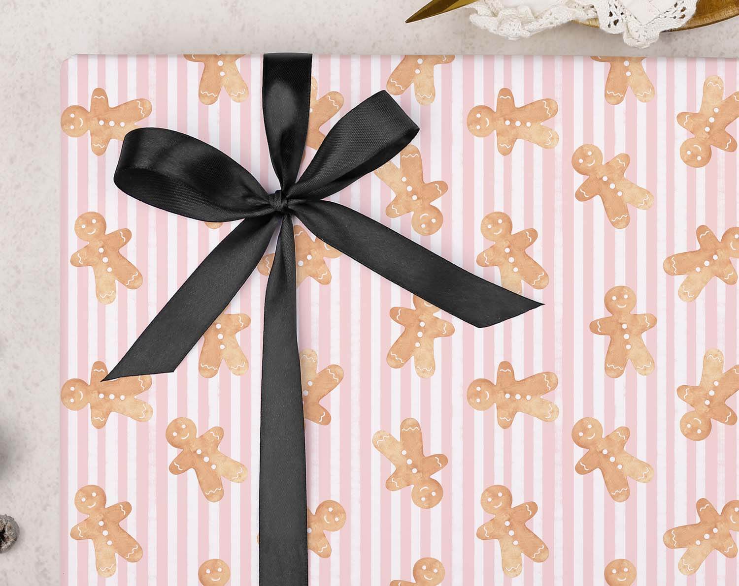 Pink Gingerbread Christmas Wrapping Paper featuring gingerbread men and a black ribbon bow.