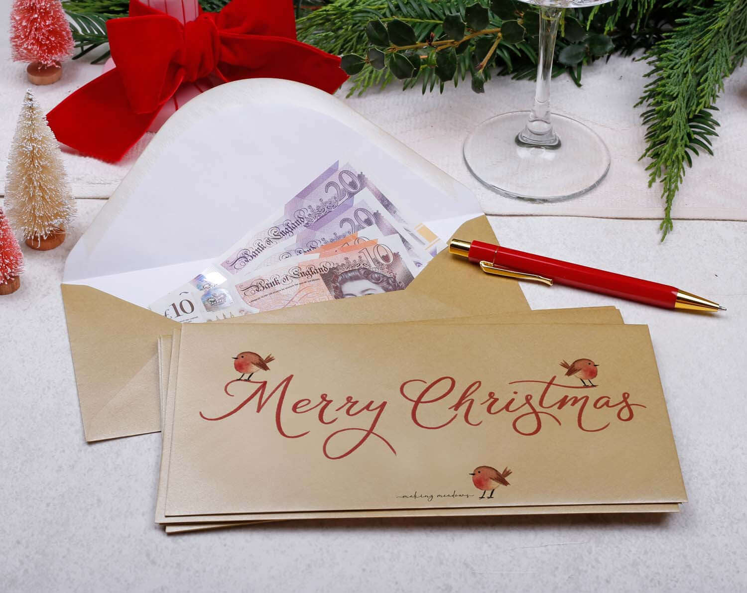 Robin Christmas Money Envelopes in gold with festive Merry Christmas design and cash inside on a Christmas-themed table.