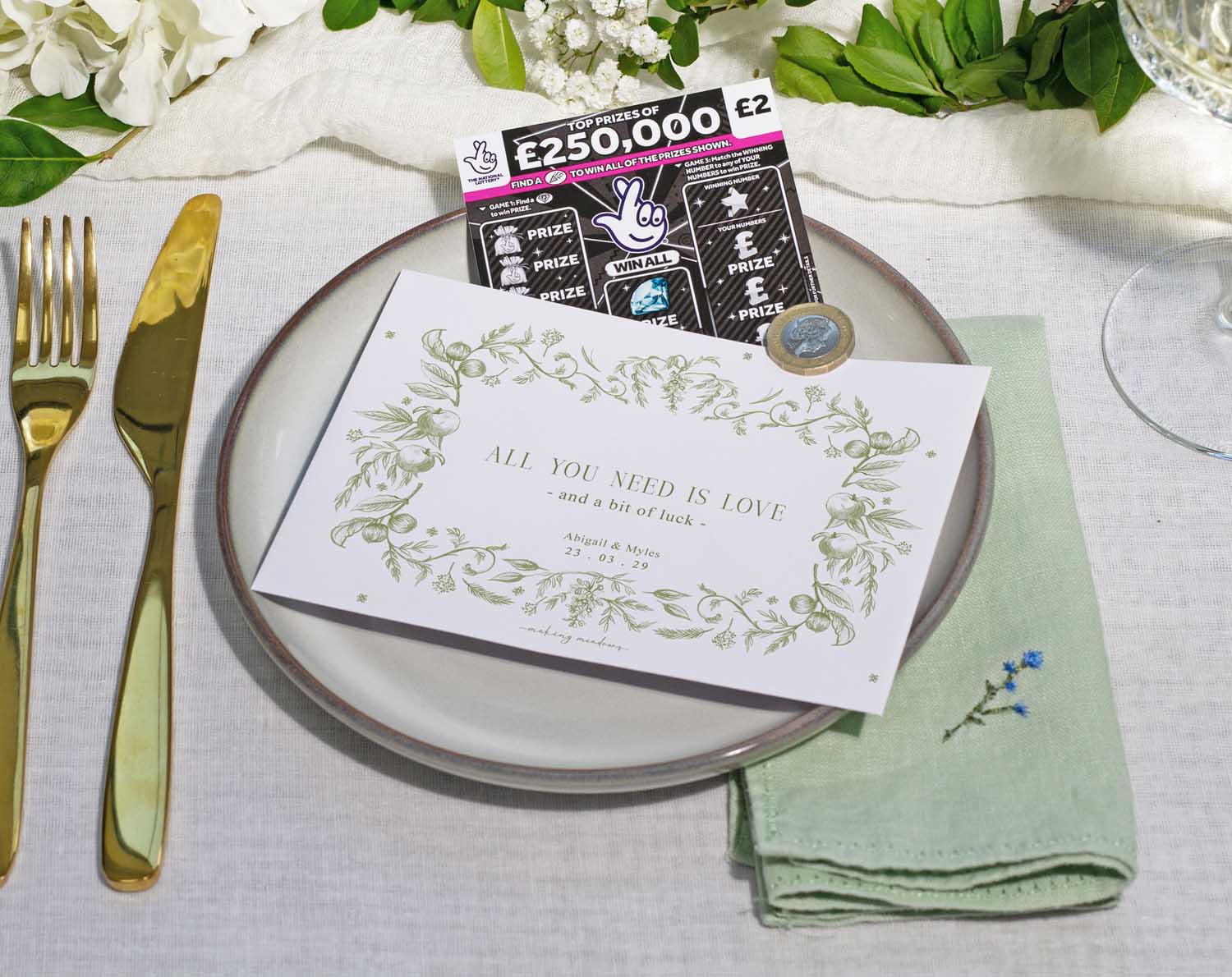 Sage Garden Scratch Card Envelopes for wedding favours on a table setting with utensils and floral decor.